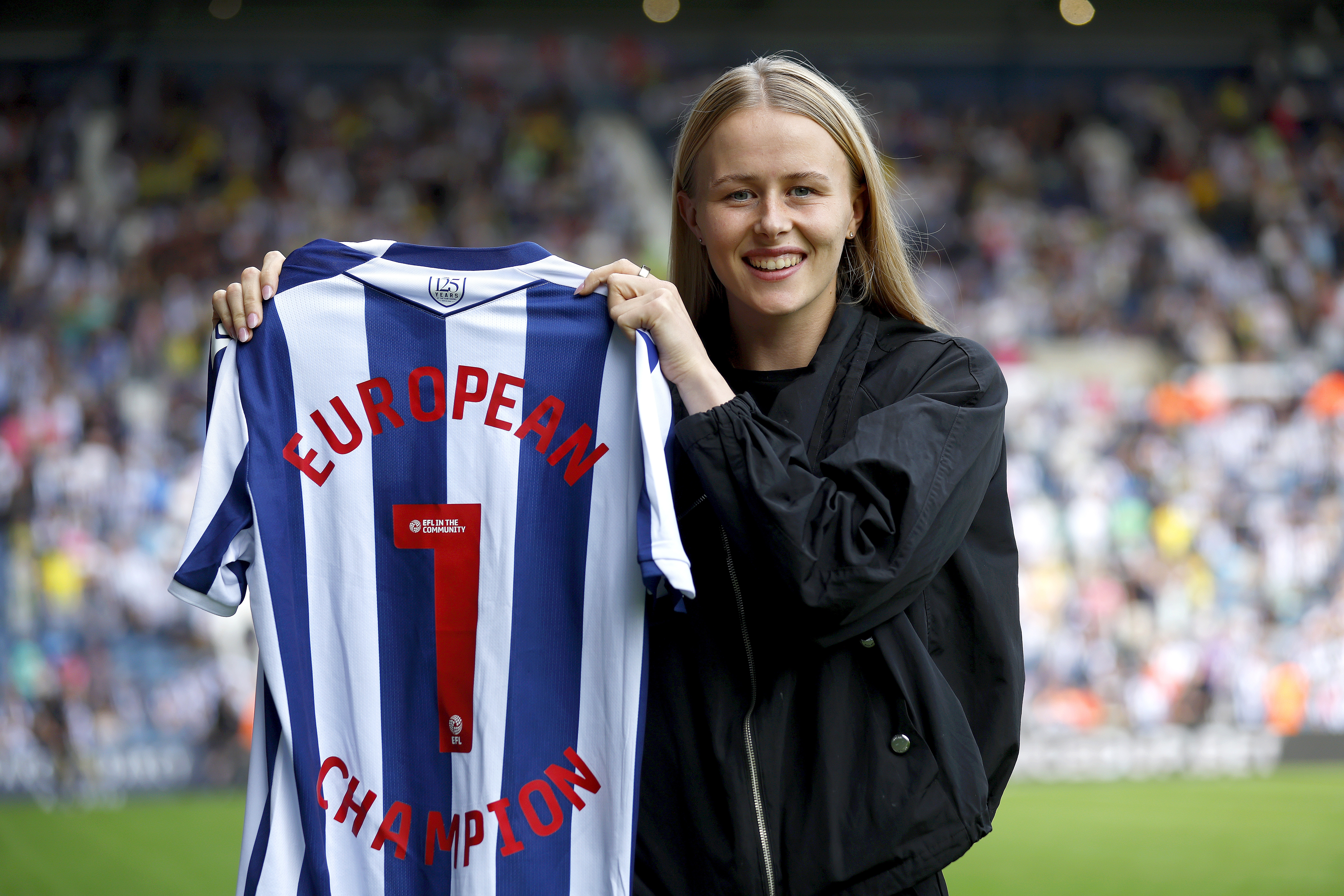 Hannah Hampton posing for a photo with an Albion shirt with her name and a No.1
