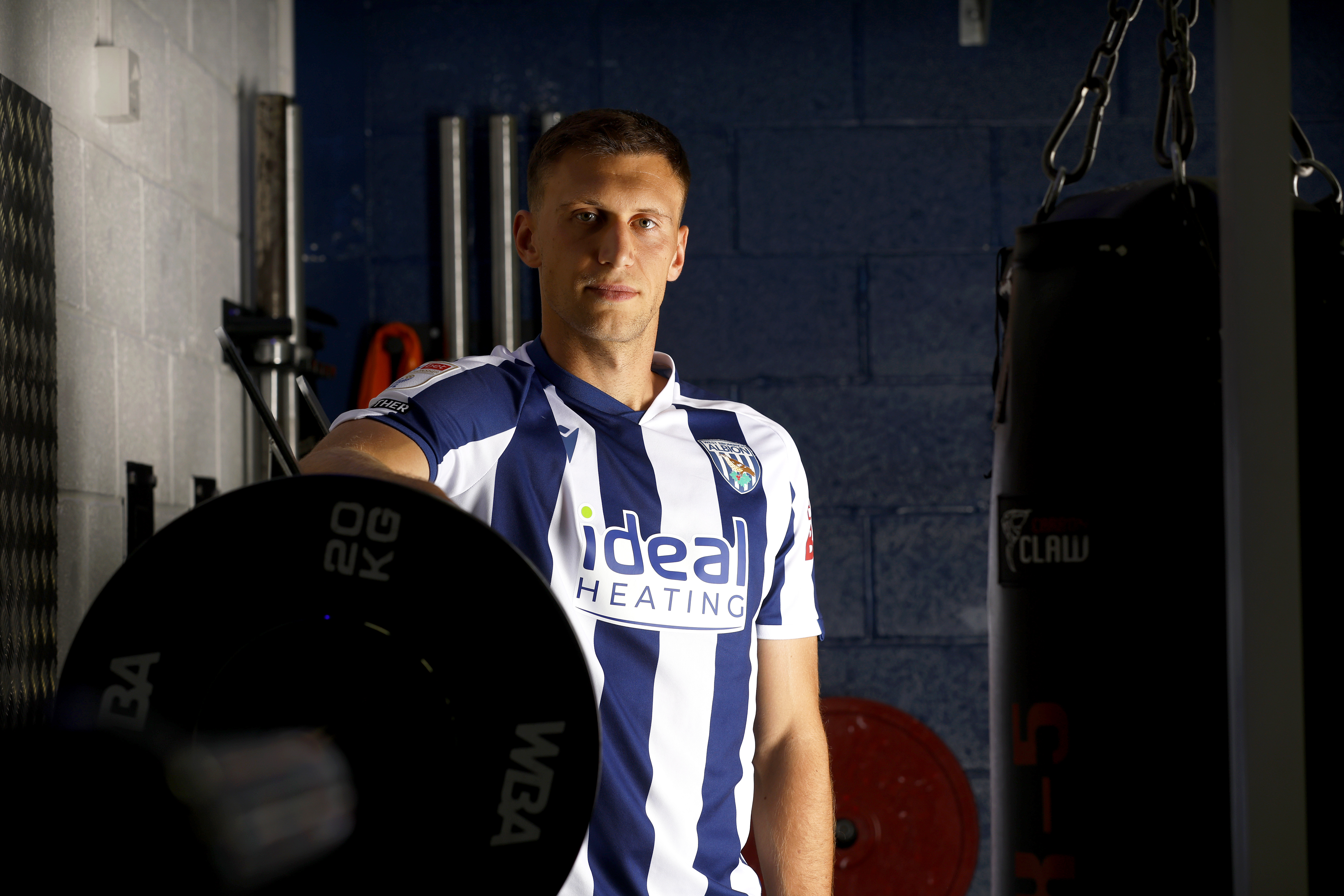 Krystian Bielik looking at the camera while stood in the gym in a home shirt 