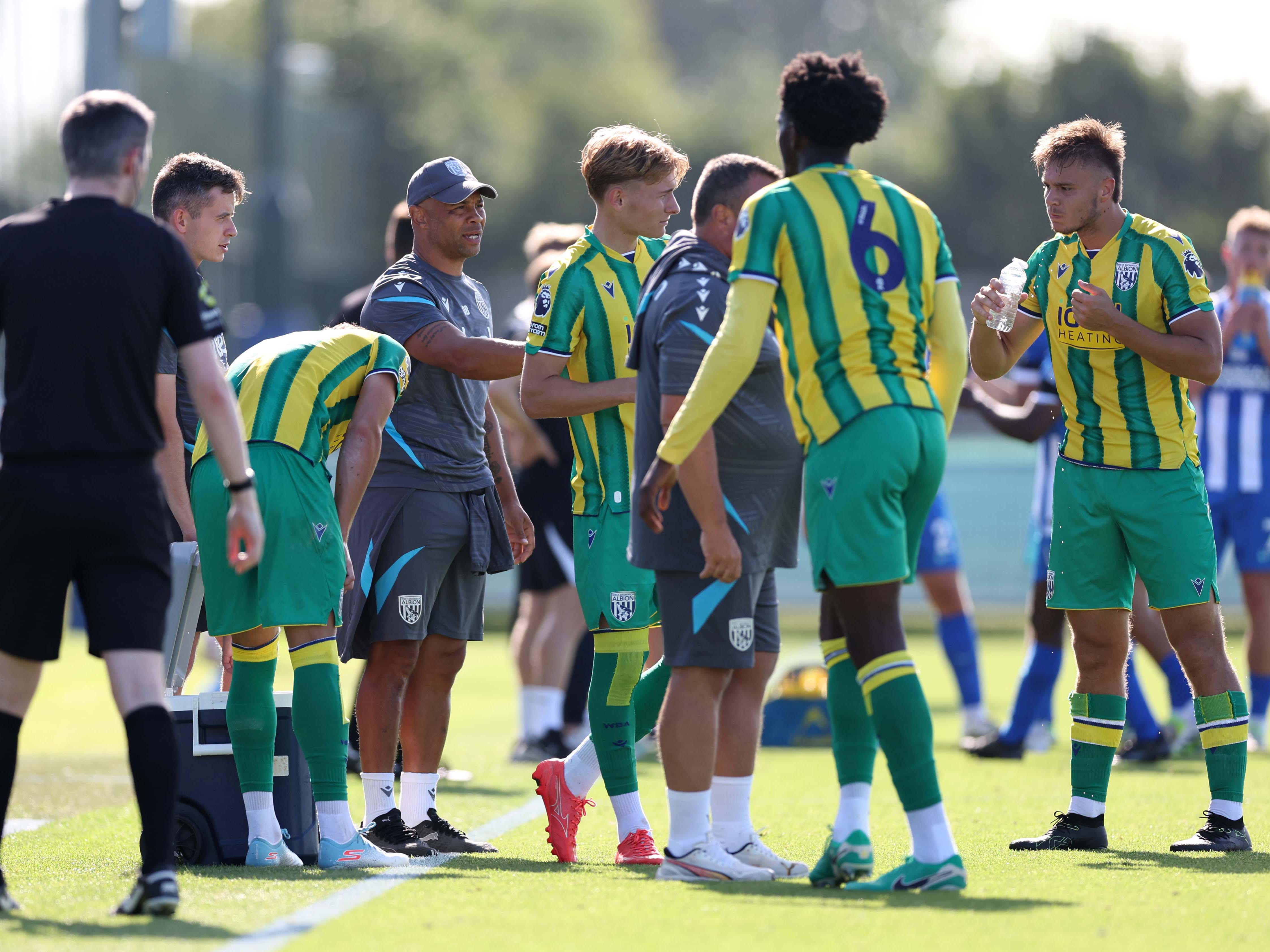 A photo of Albion U21s in the 2025/26 green and yellow away kit having a drinks break against Brighton