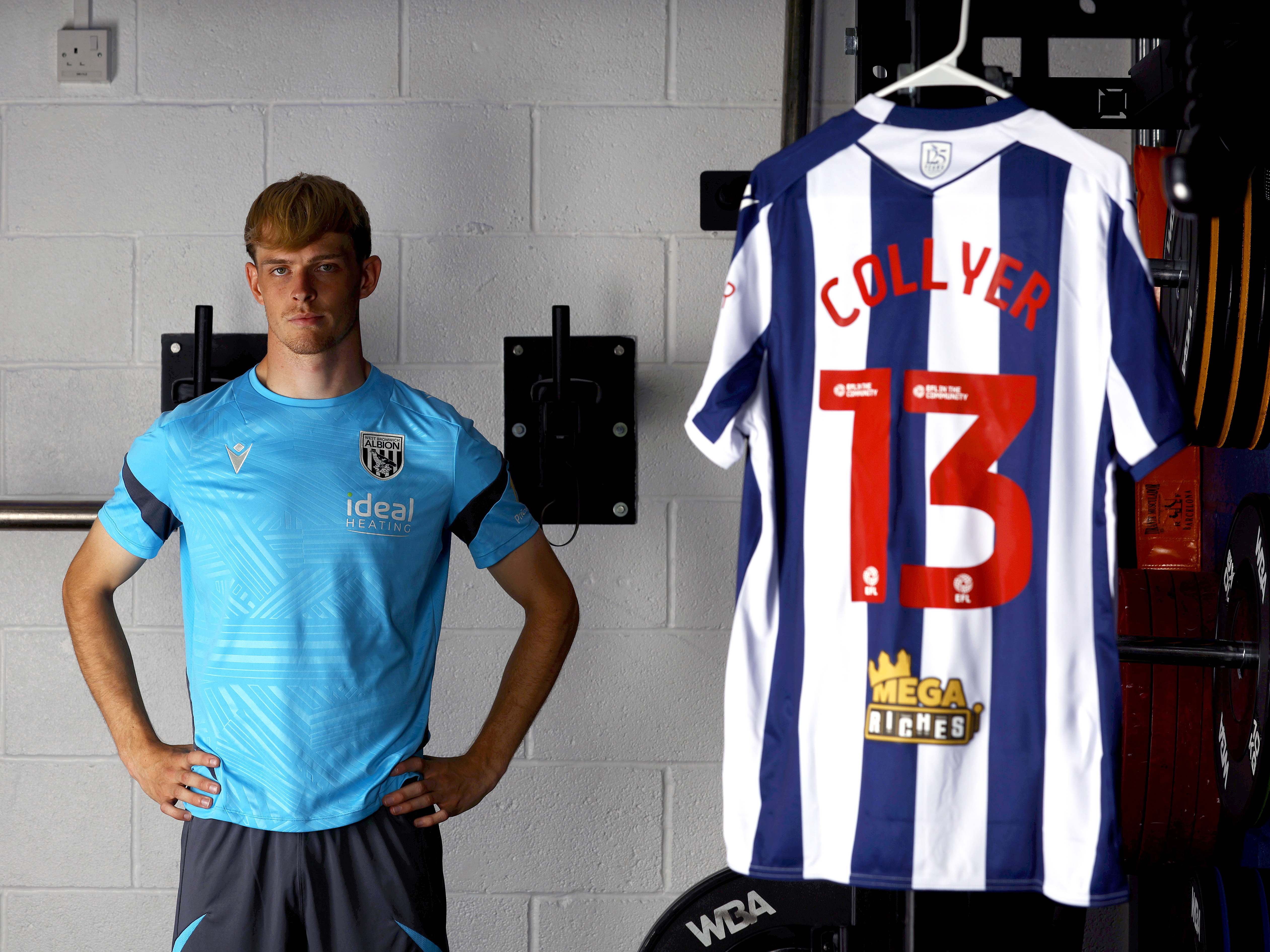 Toby Collyer stood in the gym with his hands on his hips with his 'Collyer 13' home shirt hanging up next to him