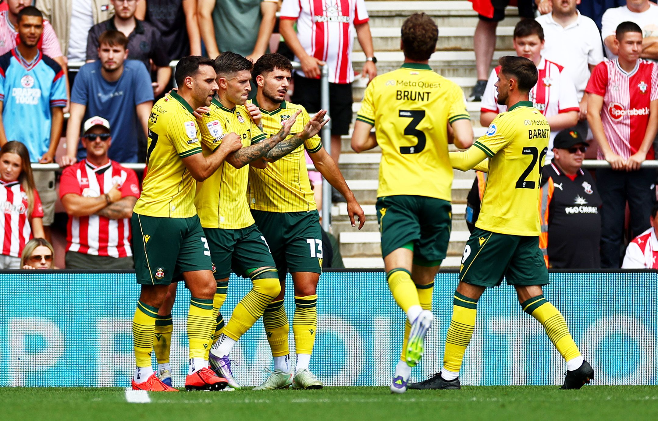 Five Wrexham players in their away kit celebrating a goal scored at Southampton