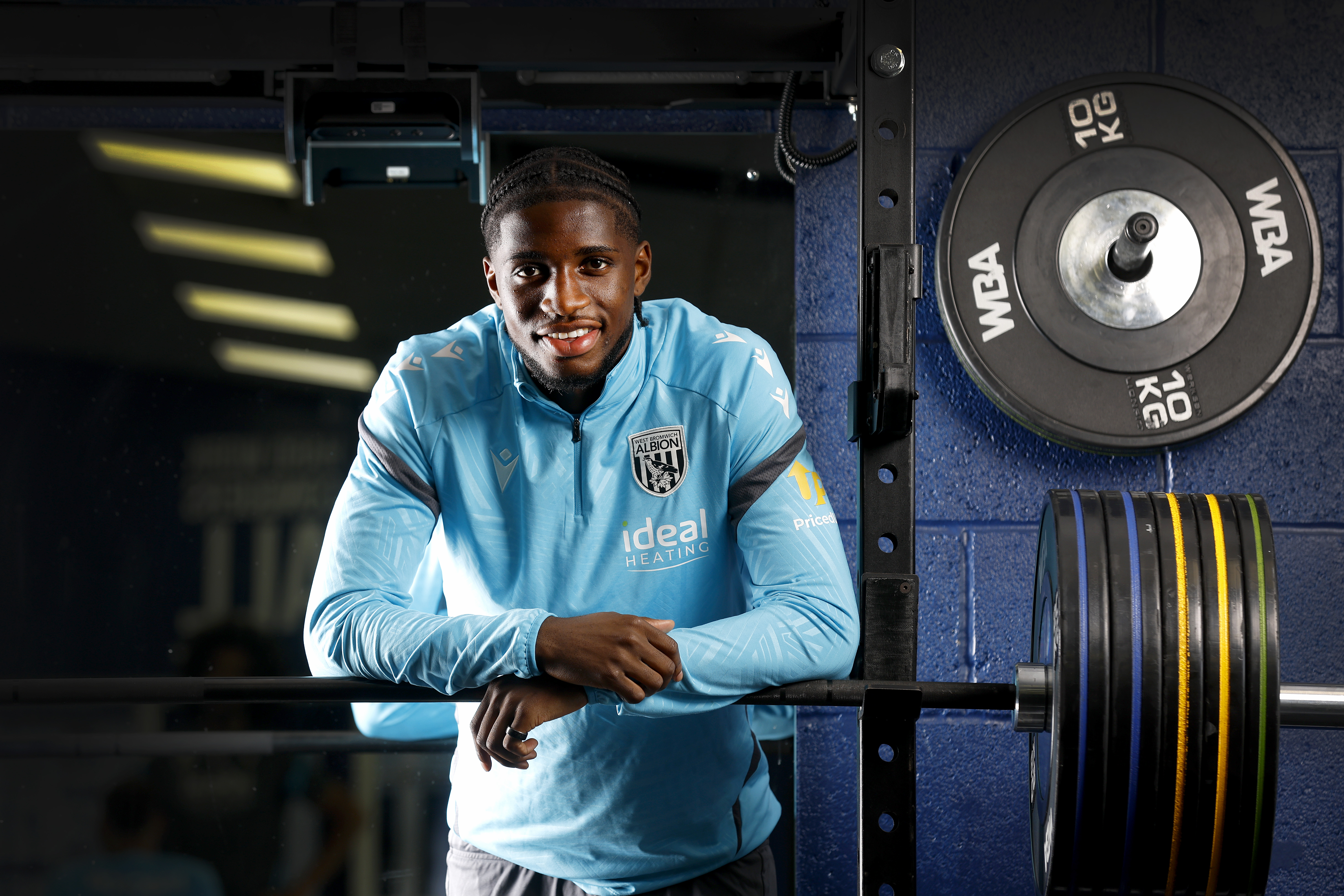 Samuel Iling-Junior smiling at the camera while leaning on a bar in the gym