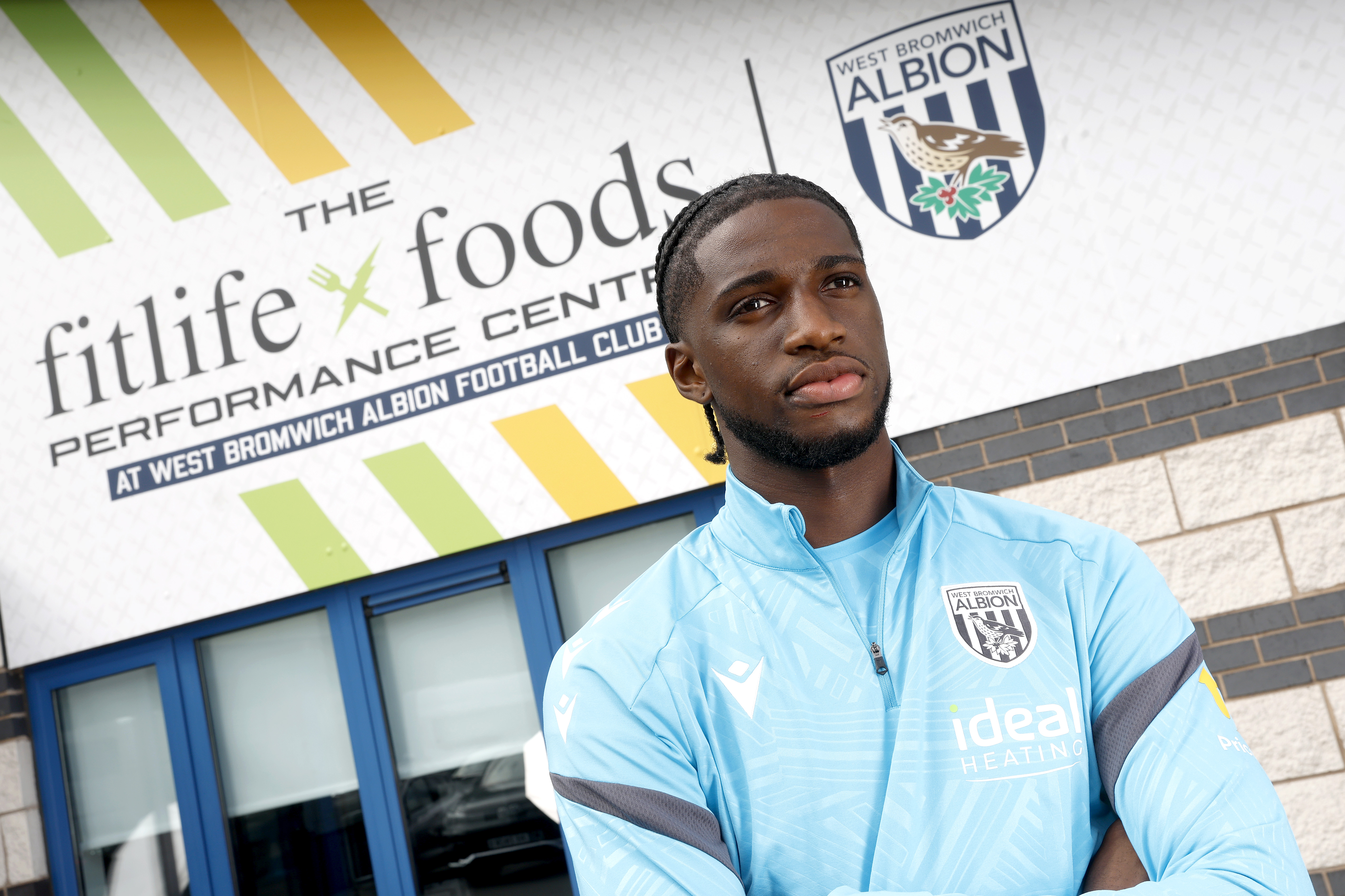 Samuel Iling-Junior looking at the camera while stood in front of branding outside the training ground