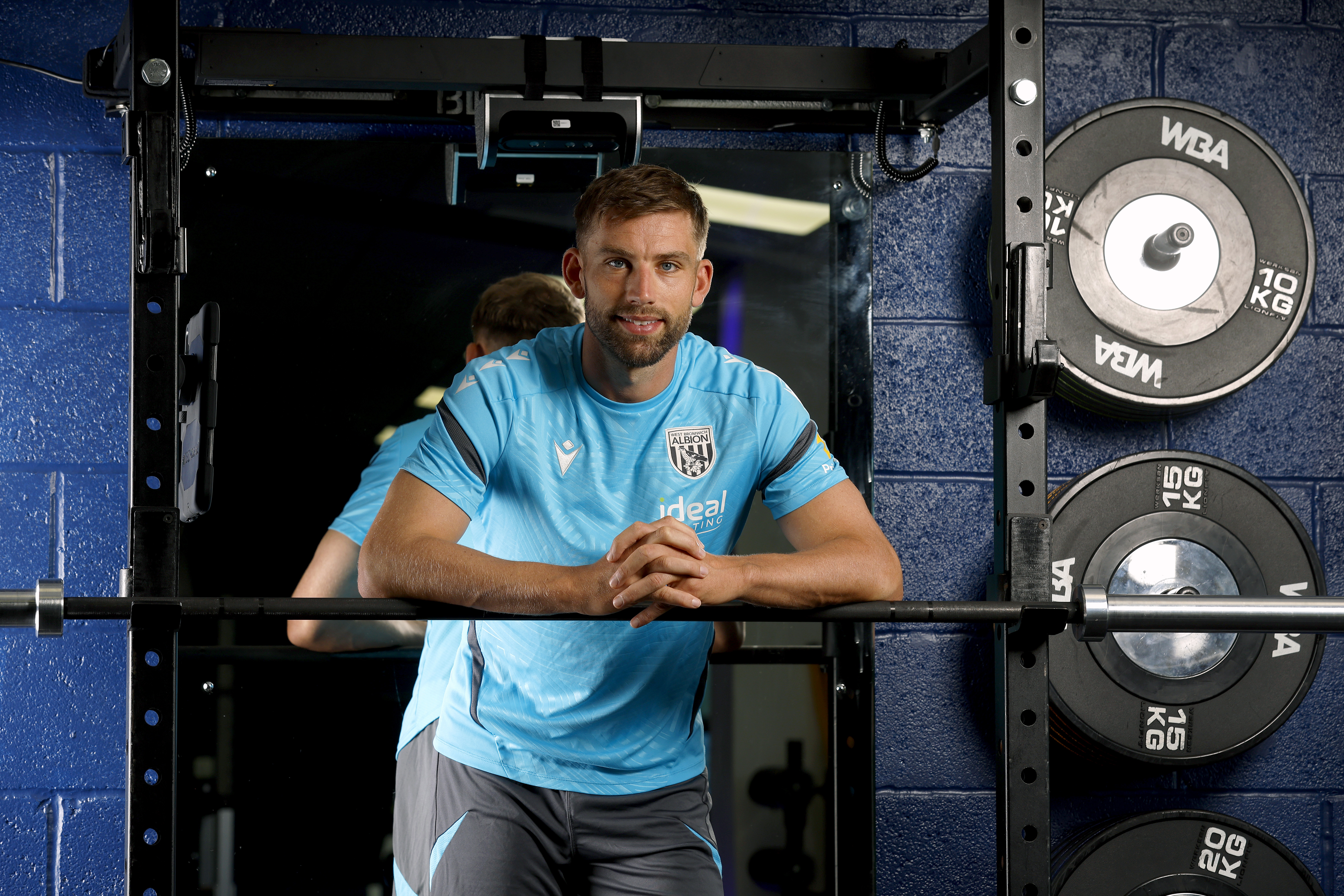 Charlie Taylor smiling at the camera while leaning on a bar in the gym