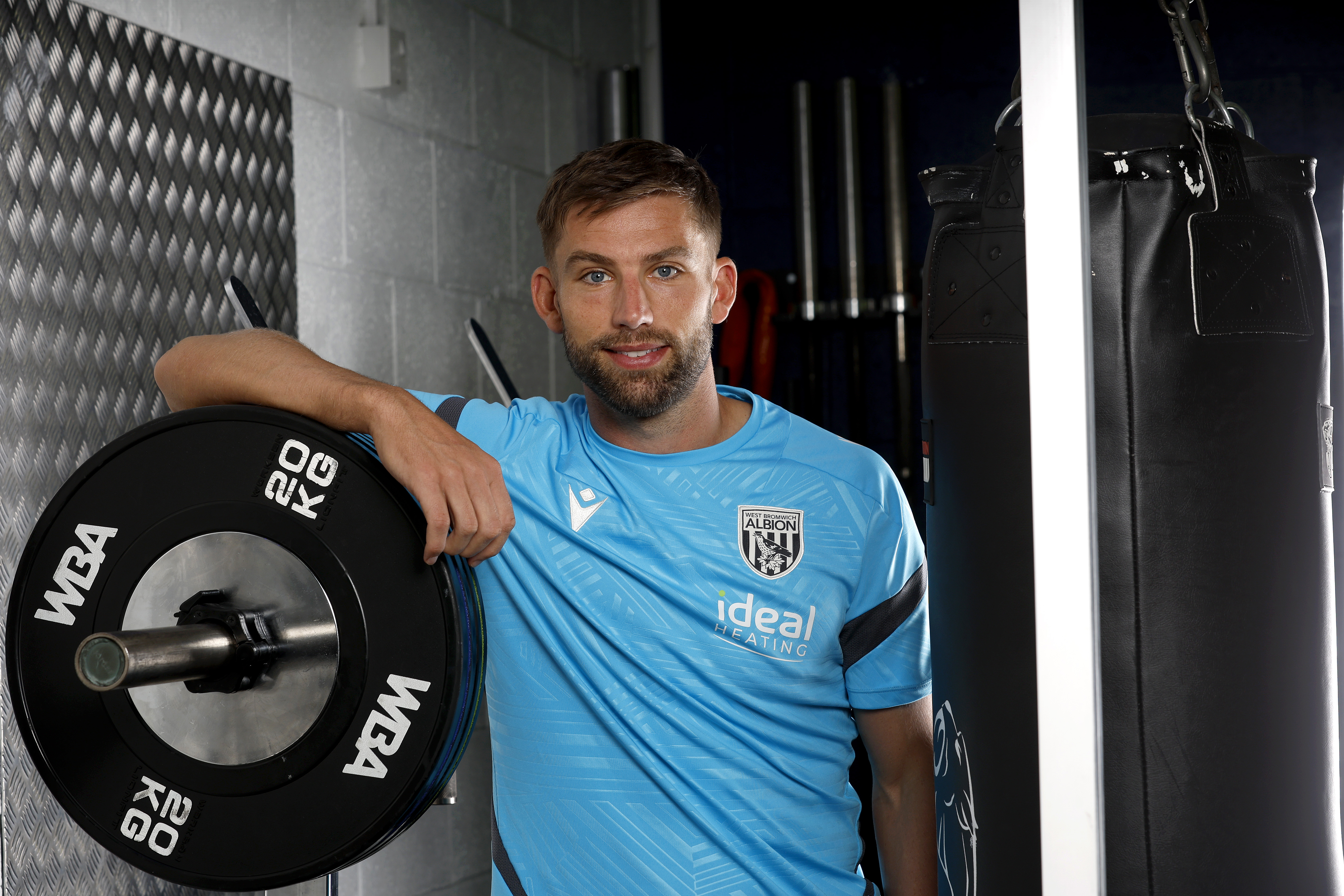 Charlie Taylor smiling at the camera while leaning on weights in the gym