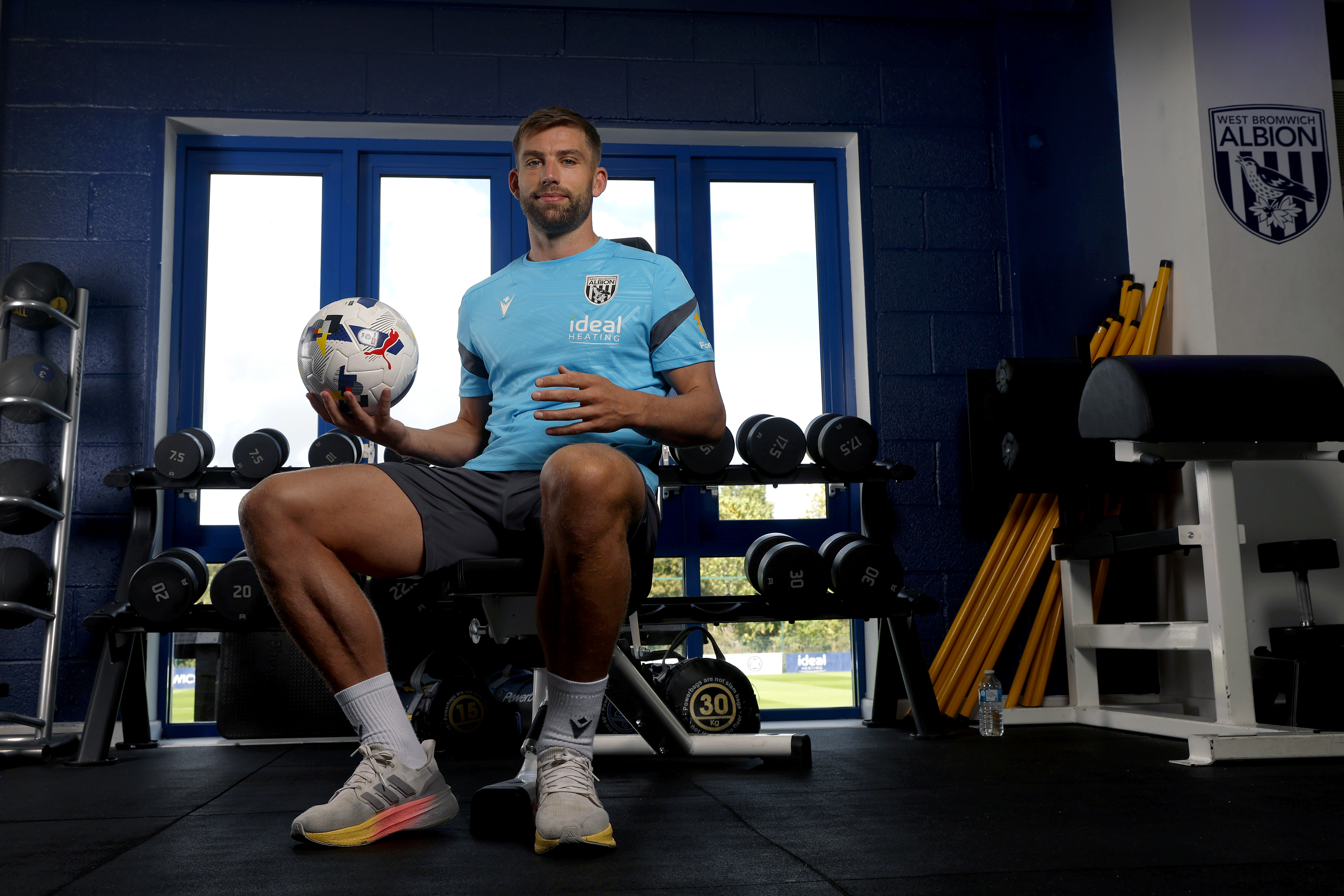 Charlie Taylor smiling at the camera while sat in the gym holding a ball