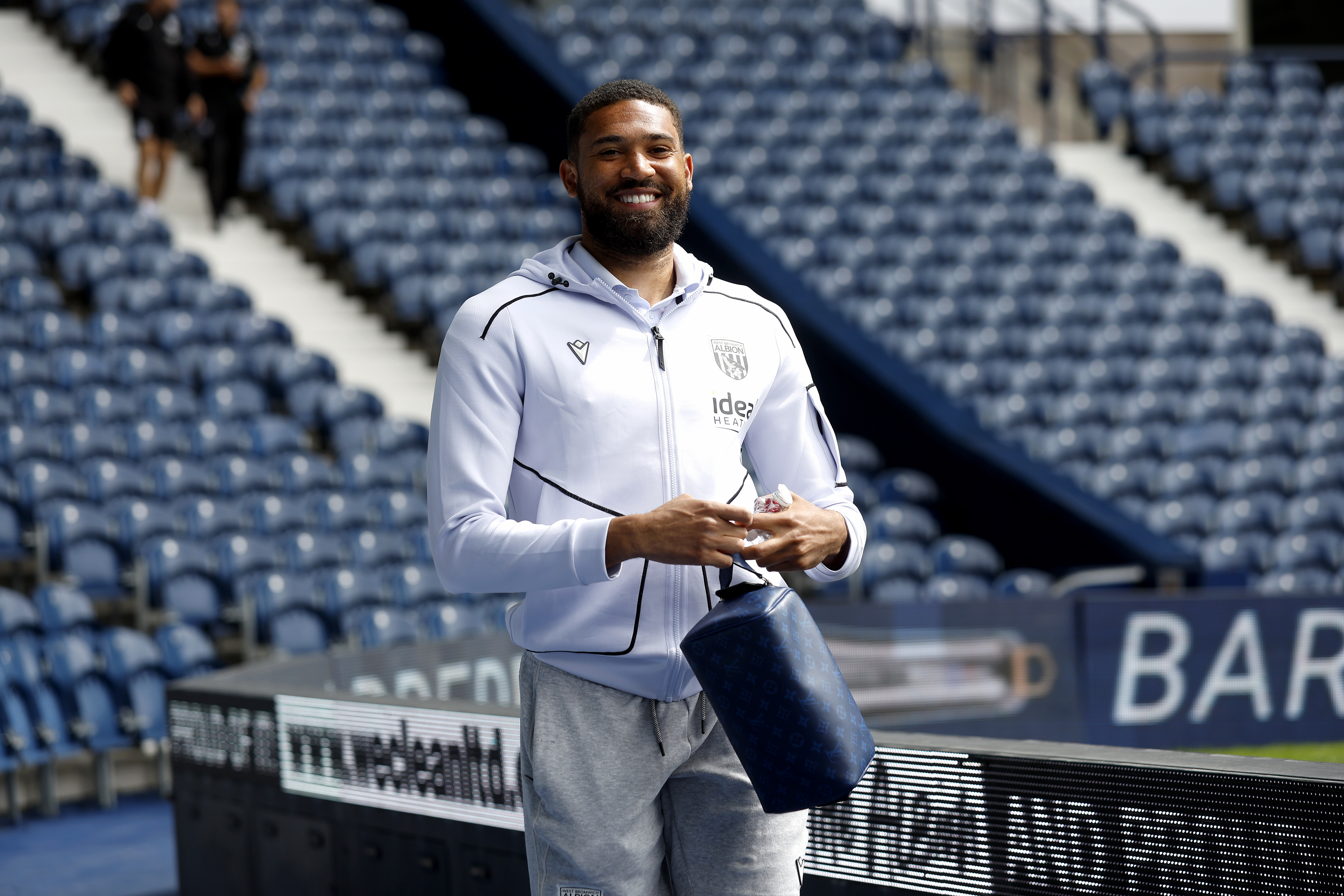 George Campbell smiling while arriving at The Hawthorns in a white tracksuit 