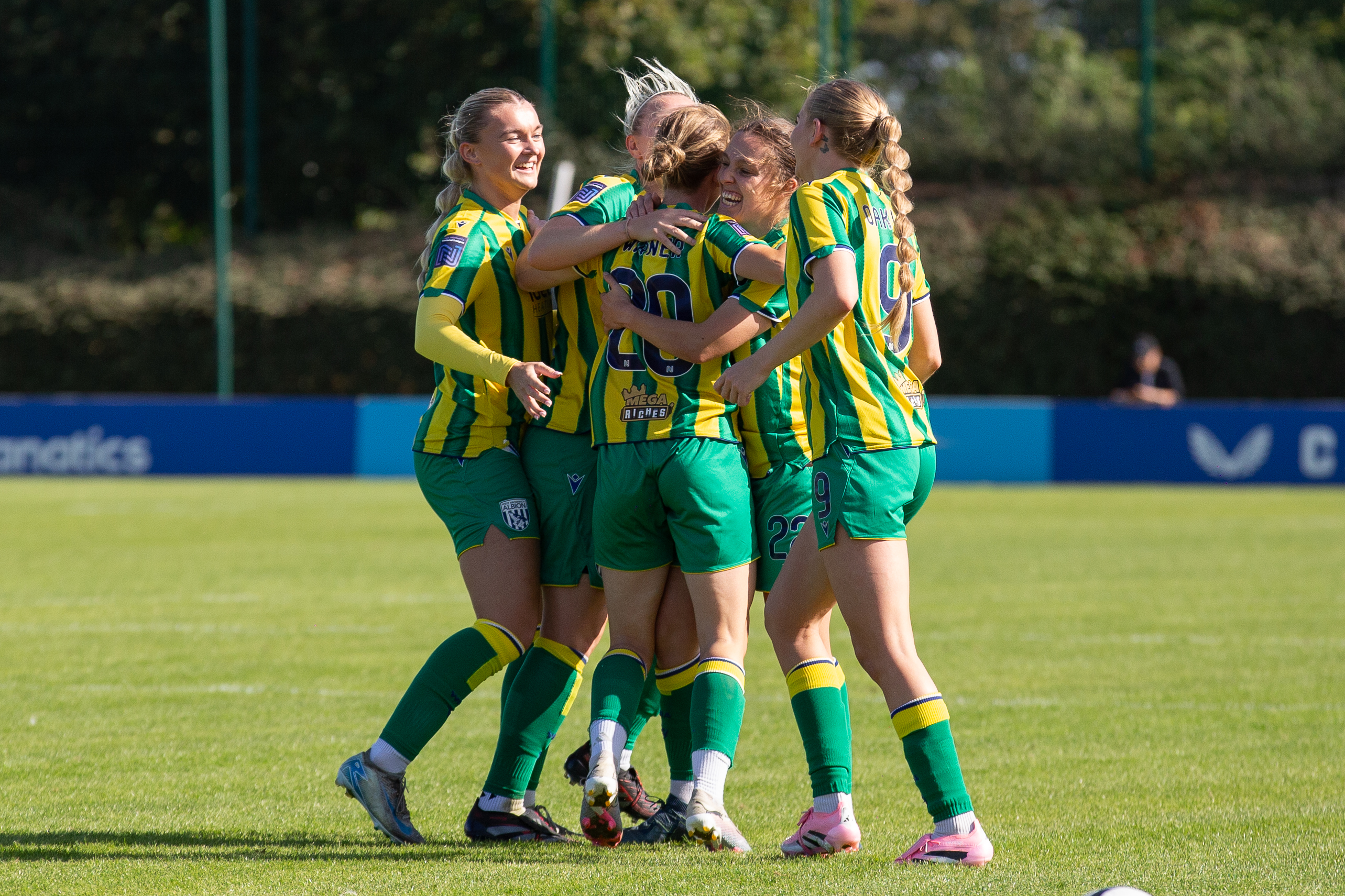Albion Women players in the green and yellow away kit celebrate a goal at Liverpool Feds