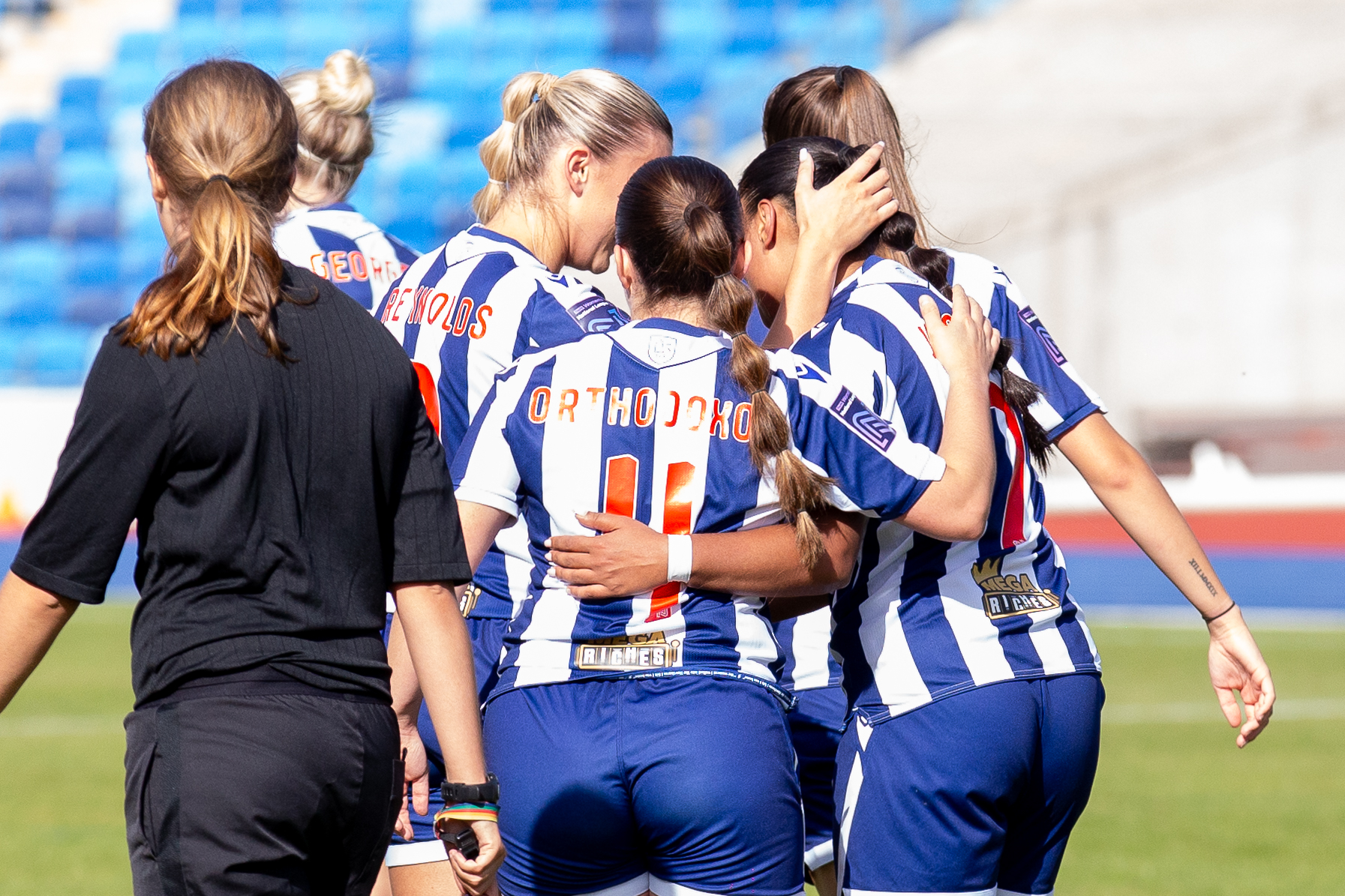 Albion women players celebrate a goal scored in the home kit 