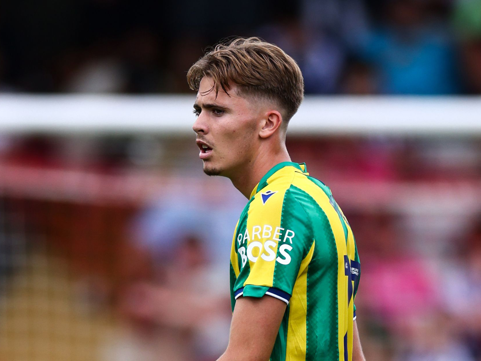 the side of Isaac Price with the player in the green and yellow away kit 