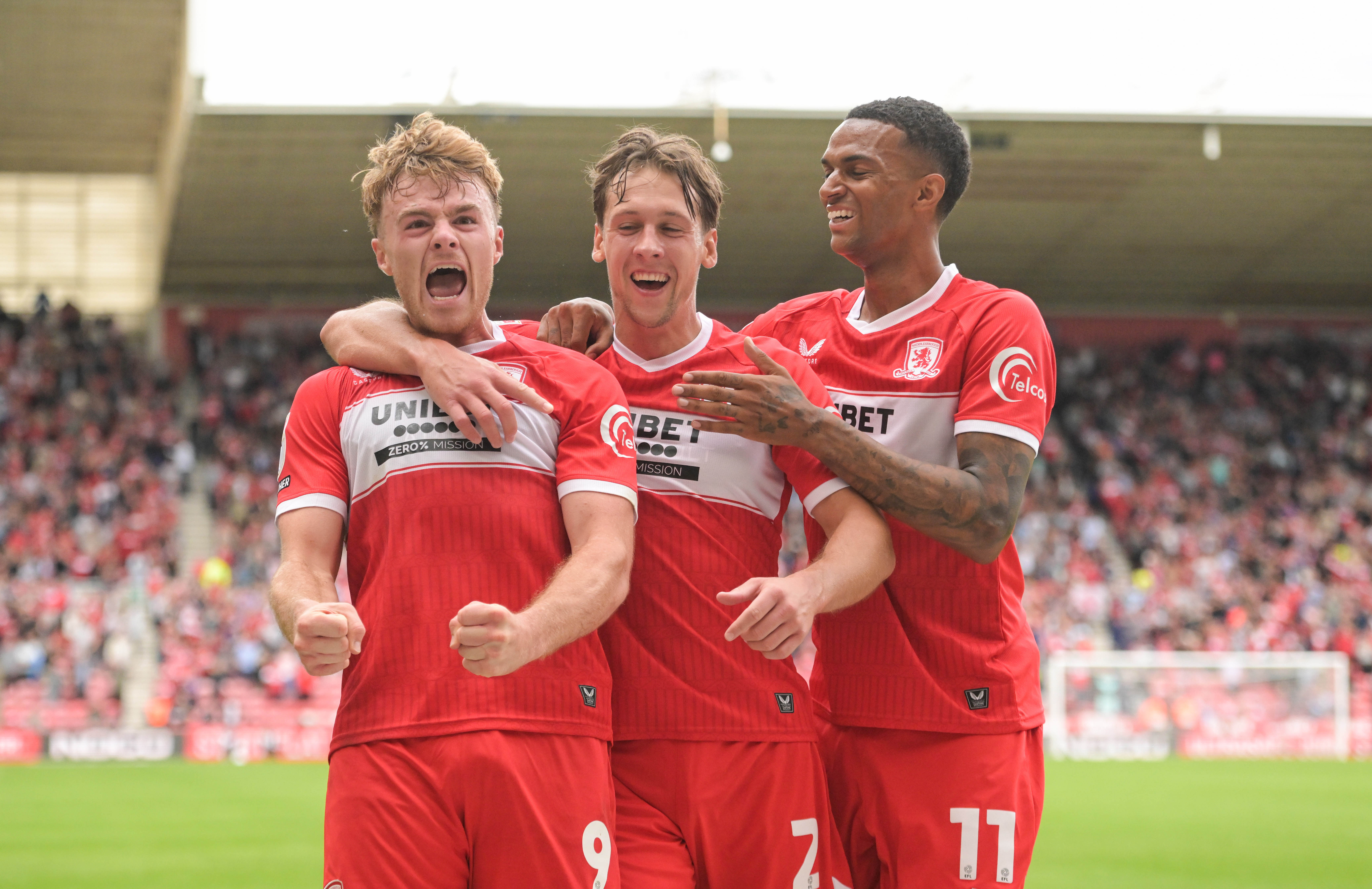 Three Middlesbrough players celebrate a goal in their home kit 