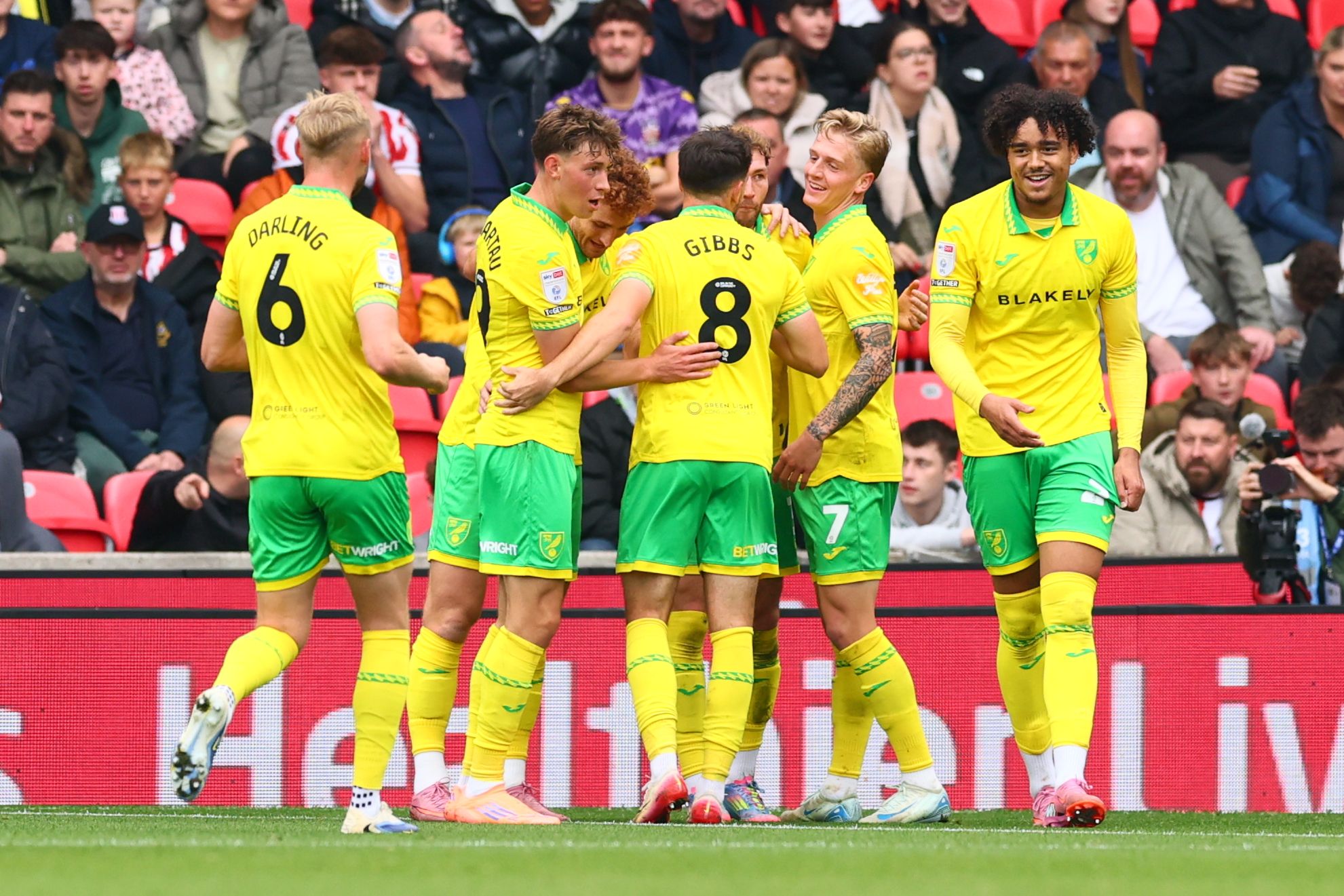 Several Norwich players celebrate a goal scored at Stoke in their home kit 