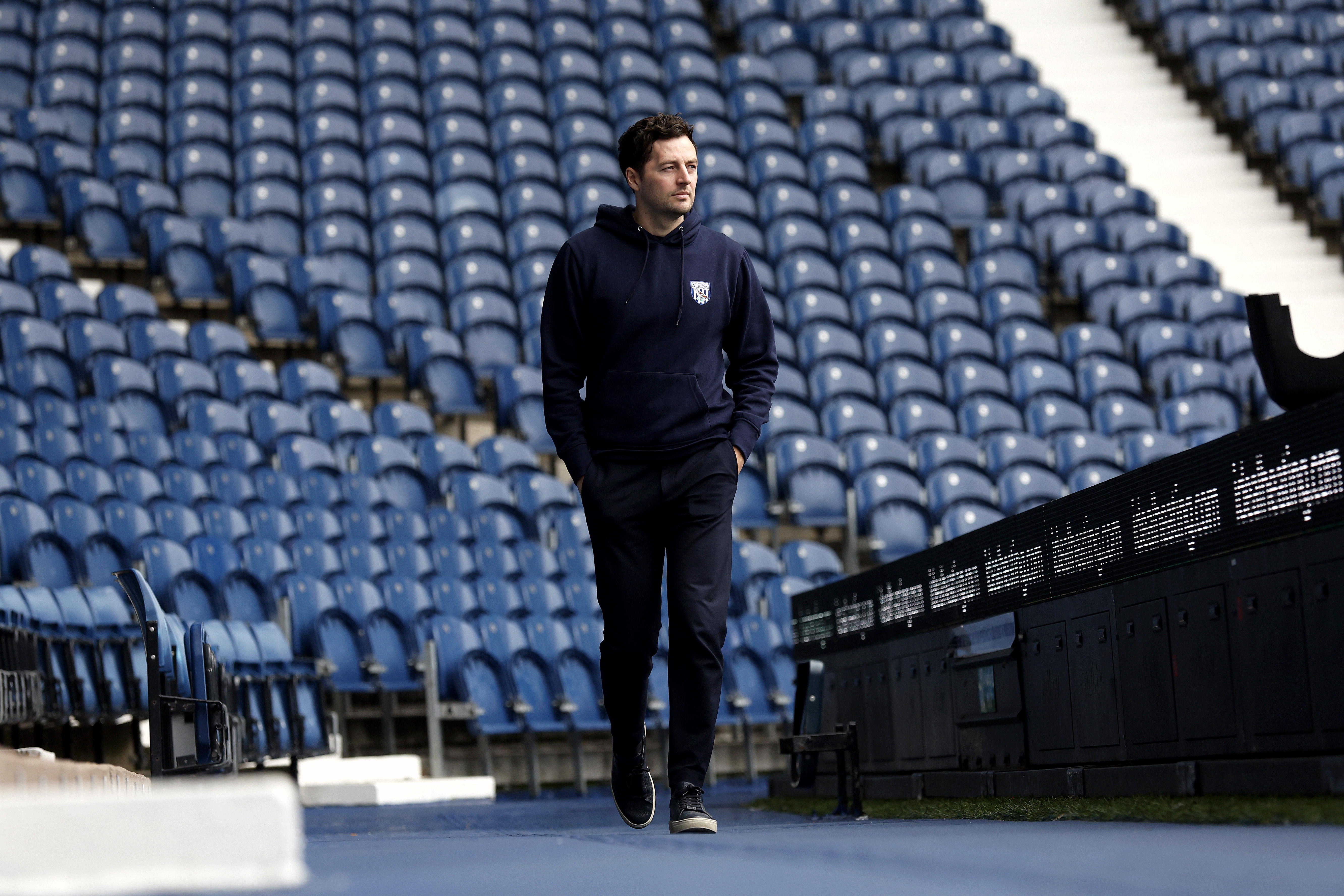 Ryan Mason walking along the blue track on the outside of the pitch at The Hawthorns