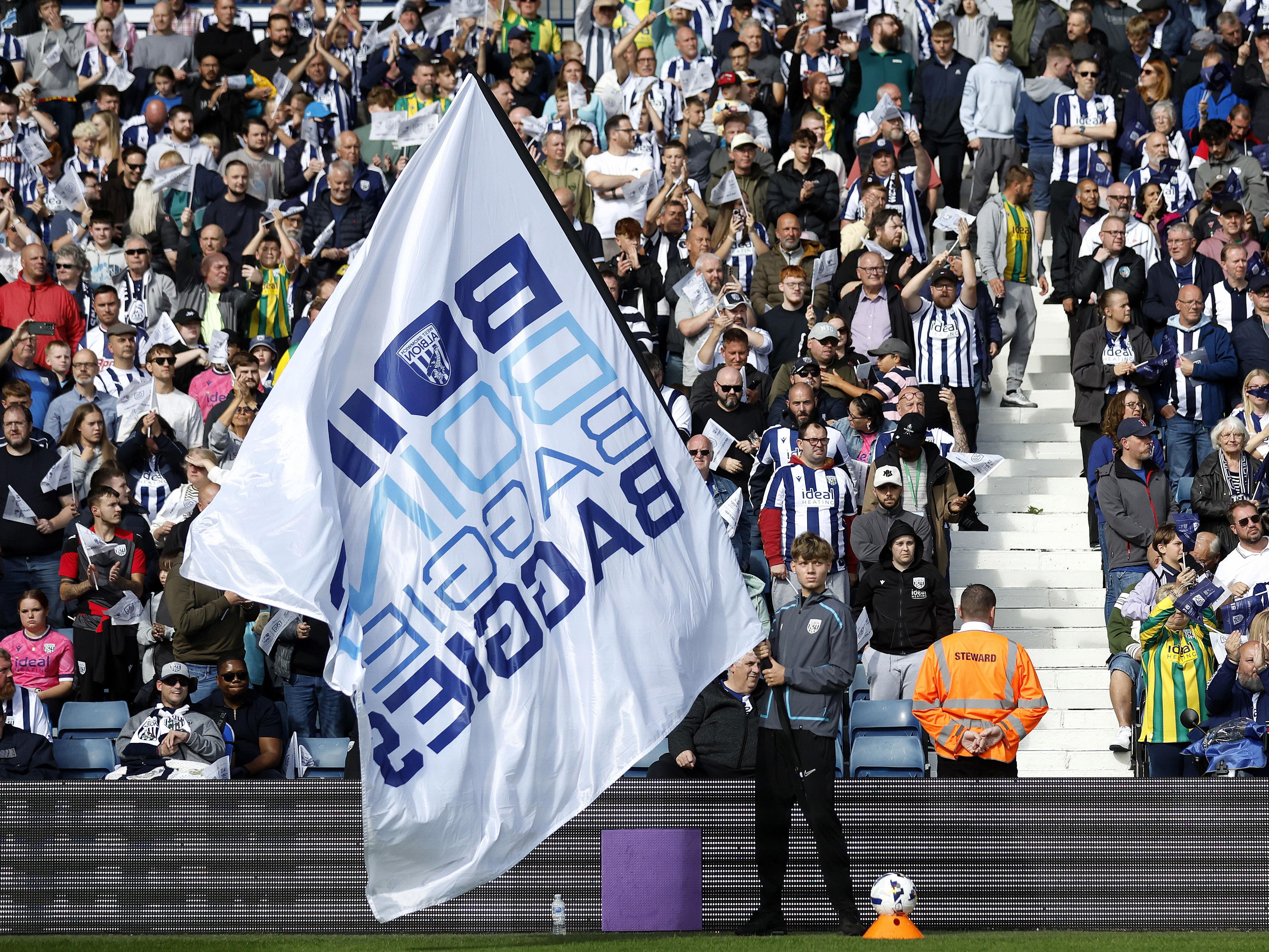 A big WBA flag waving around with supporters in the background before a game