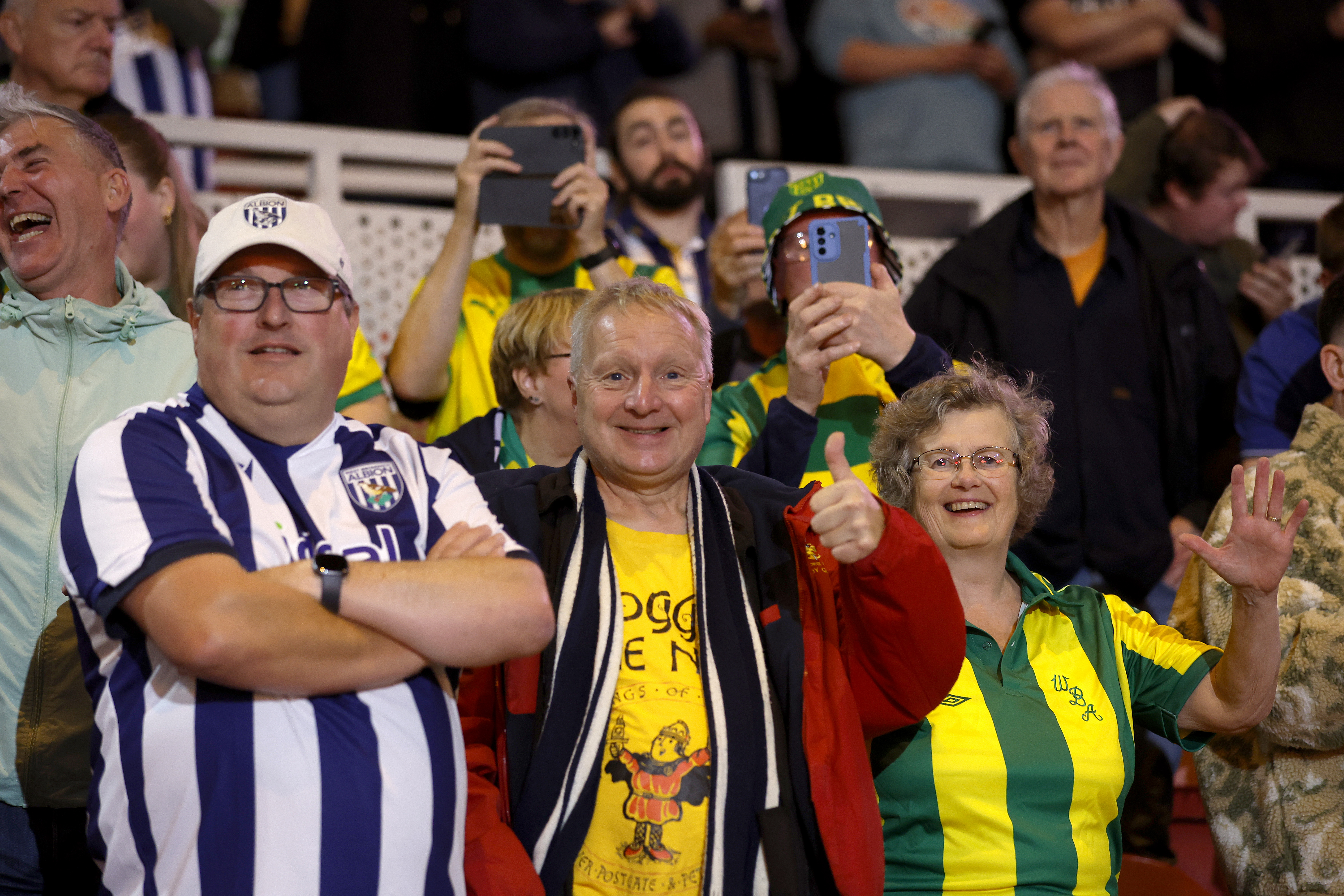 Three Albion fans smiling at the camera at a game