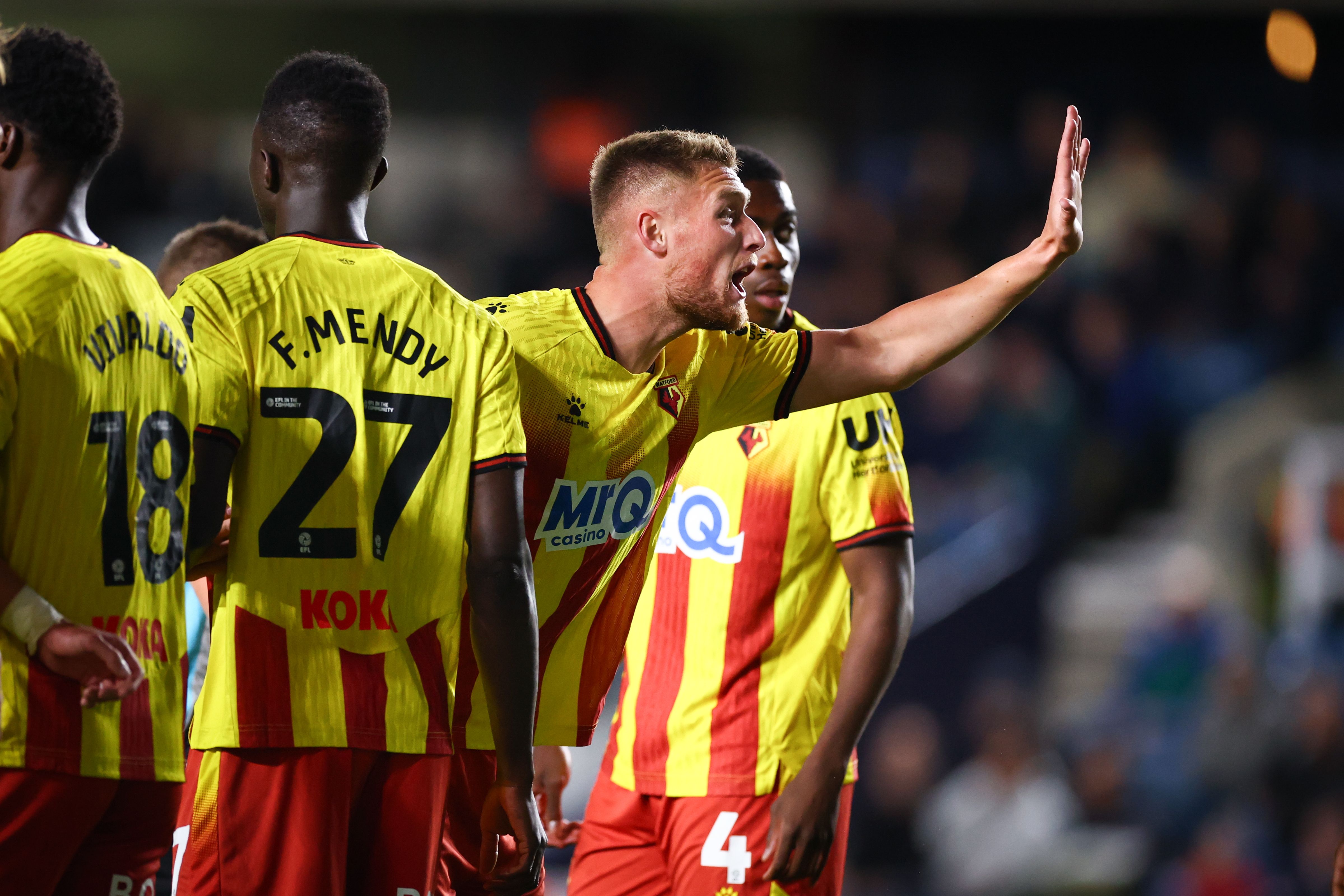 Four Watford players in a wall during a game in their home kit 