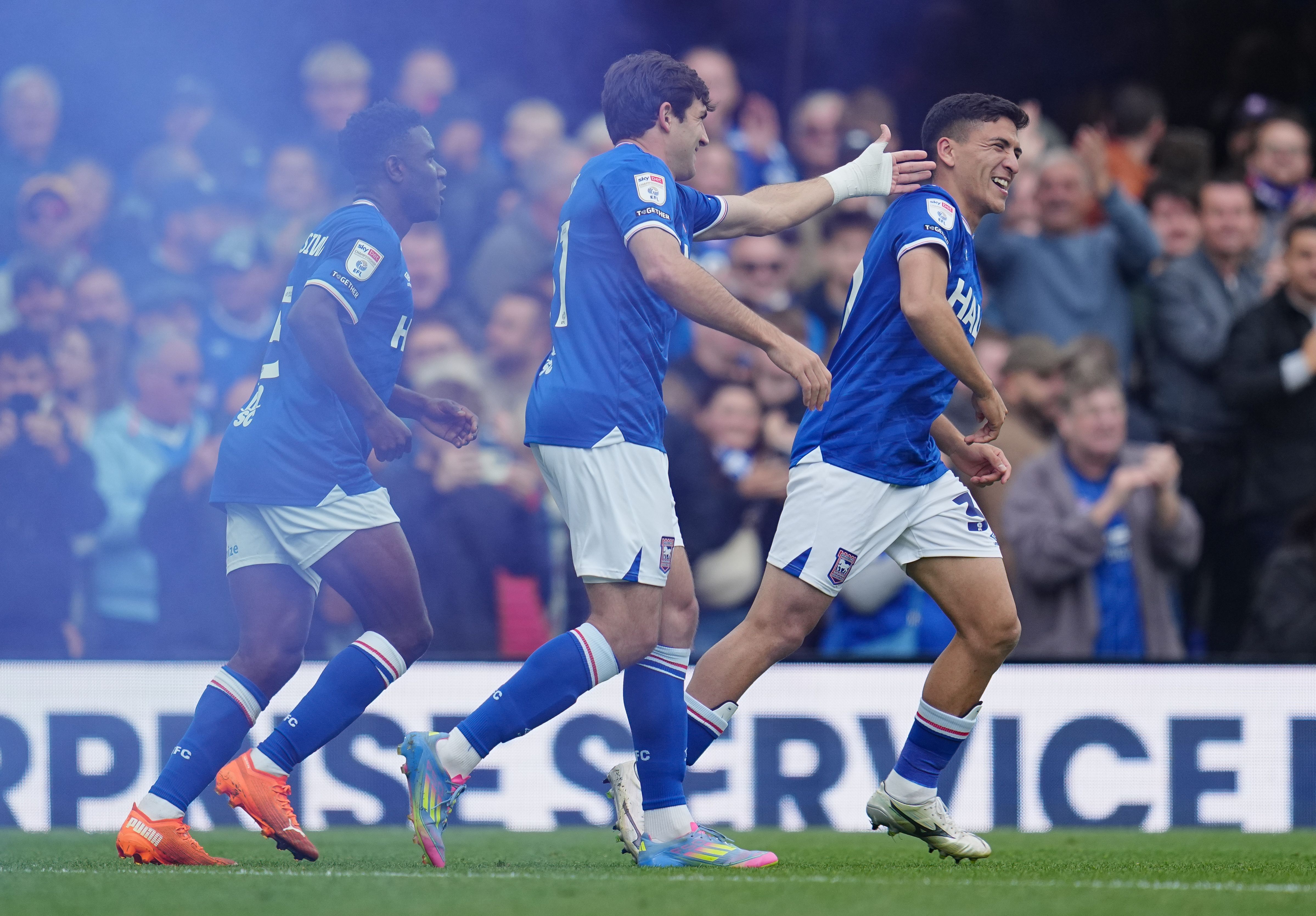 Three Ipswich players celebrating a goal in their home kit
