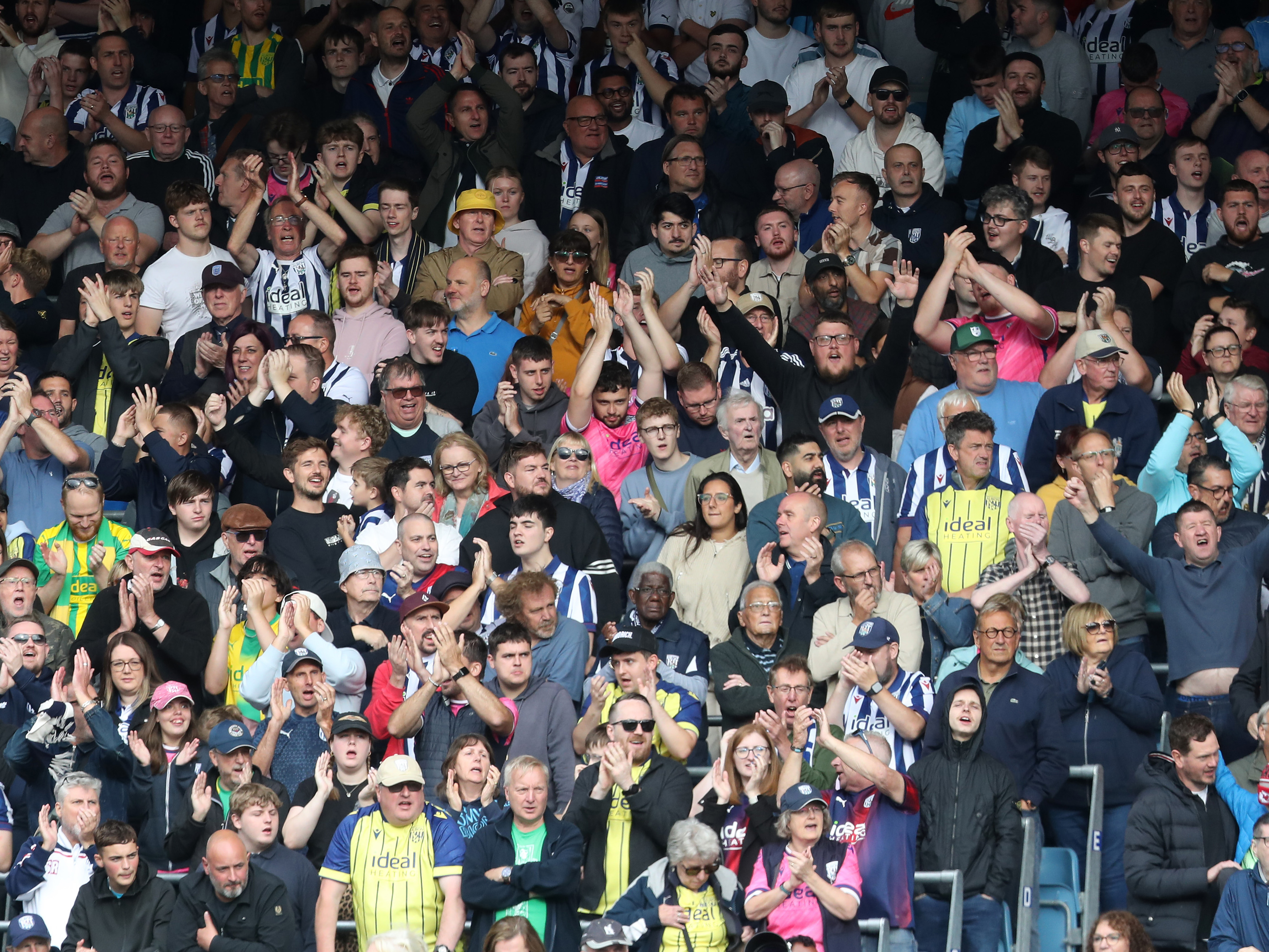 A general view of several Albion fans clapping at a game 