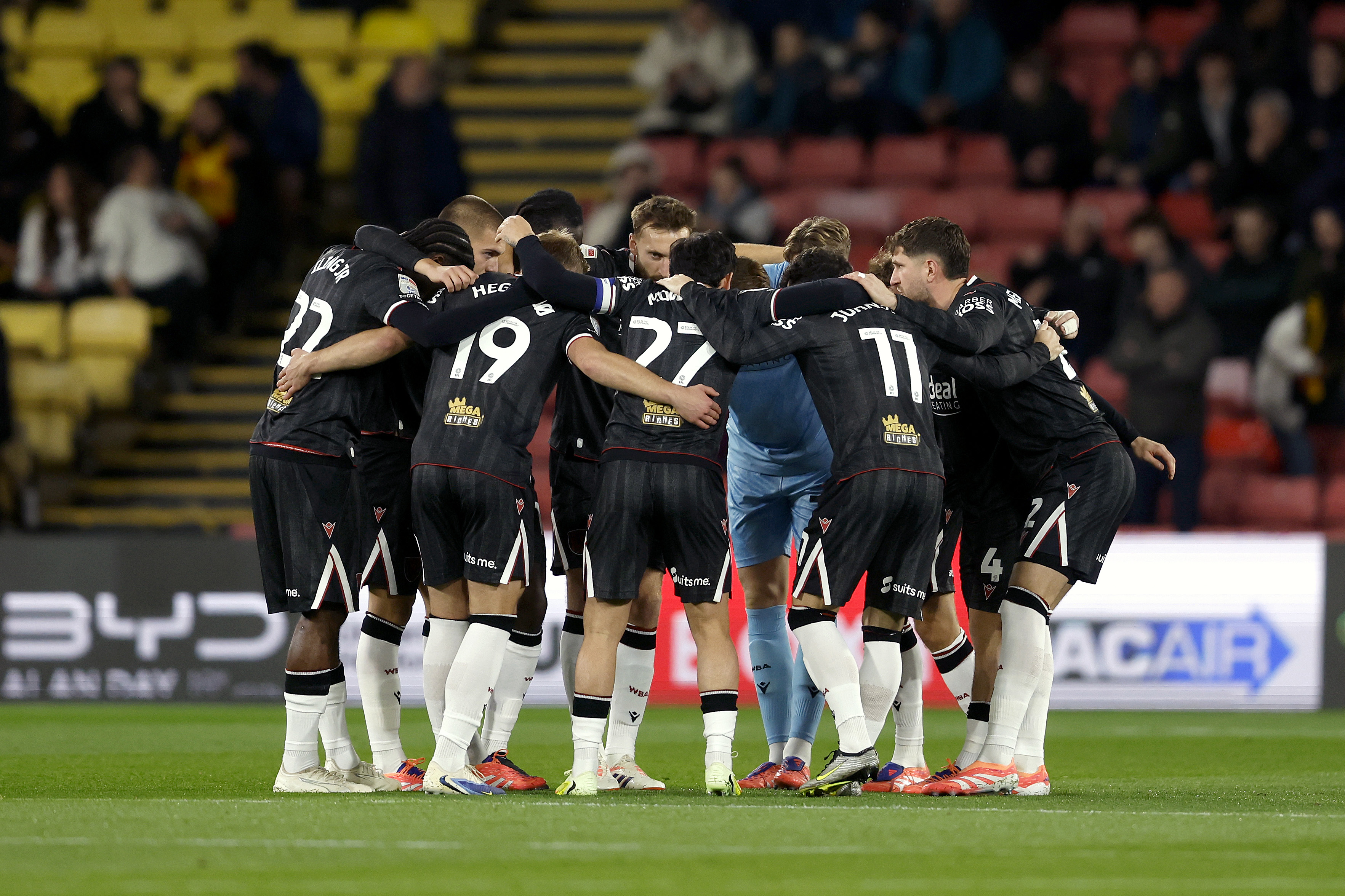 Albion players in a pre-match huddle at Watford in the black away kit 
