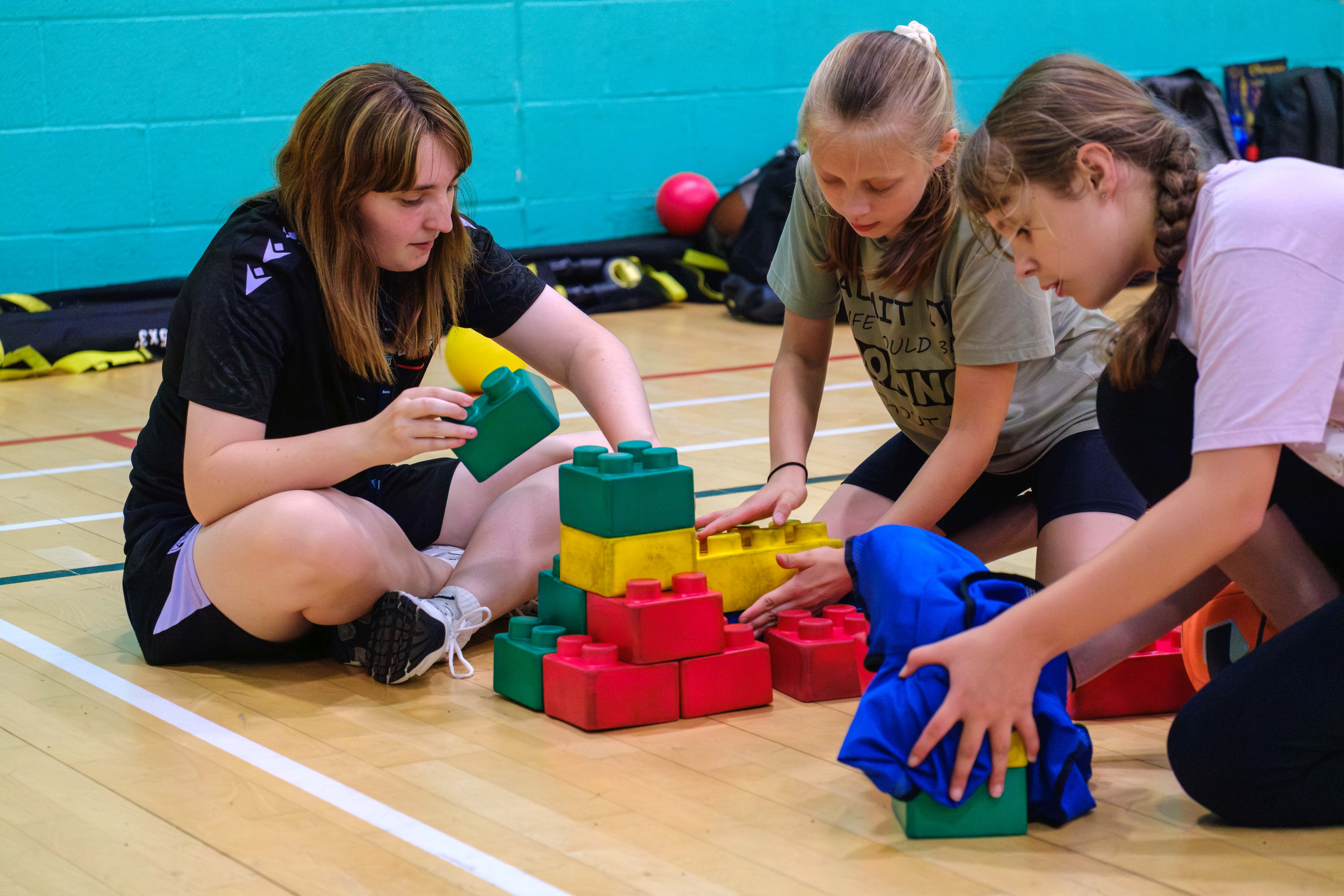 Volunteer building blocks with two young female participants.