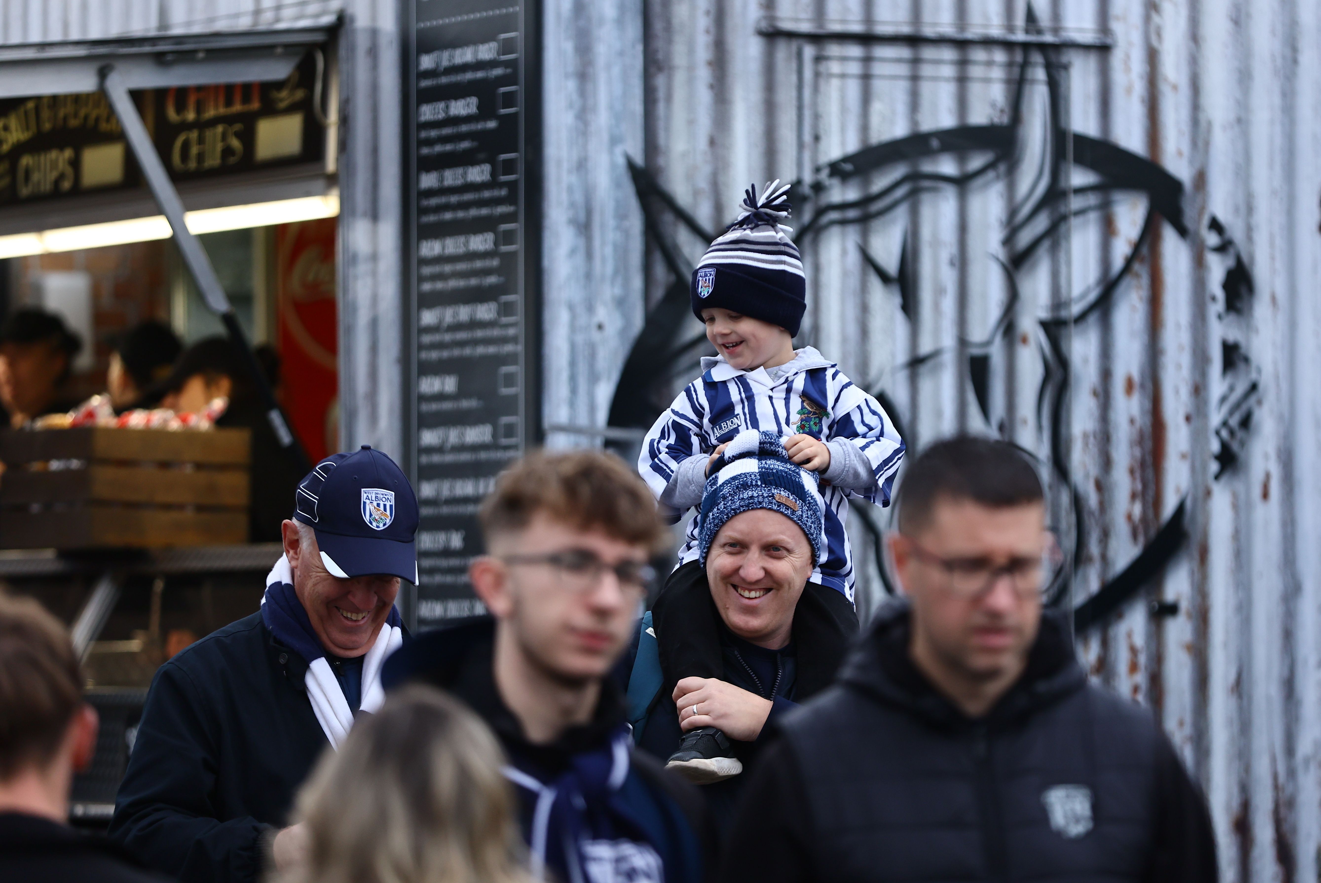 A young fan sitting on the shoulders of an adult WBA fan