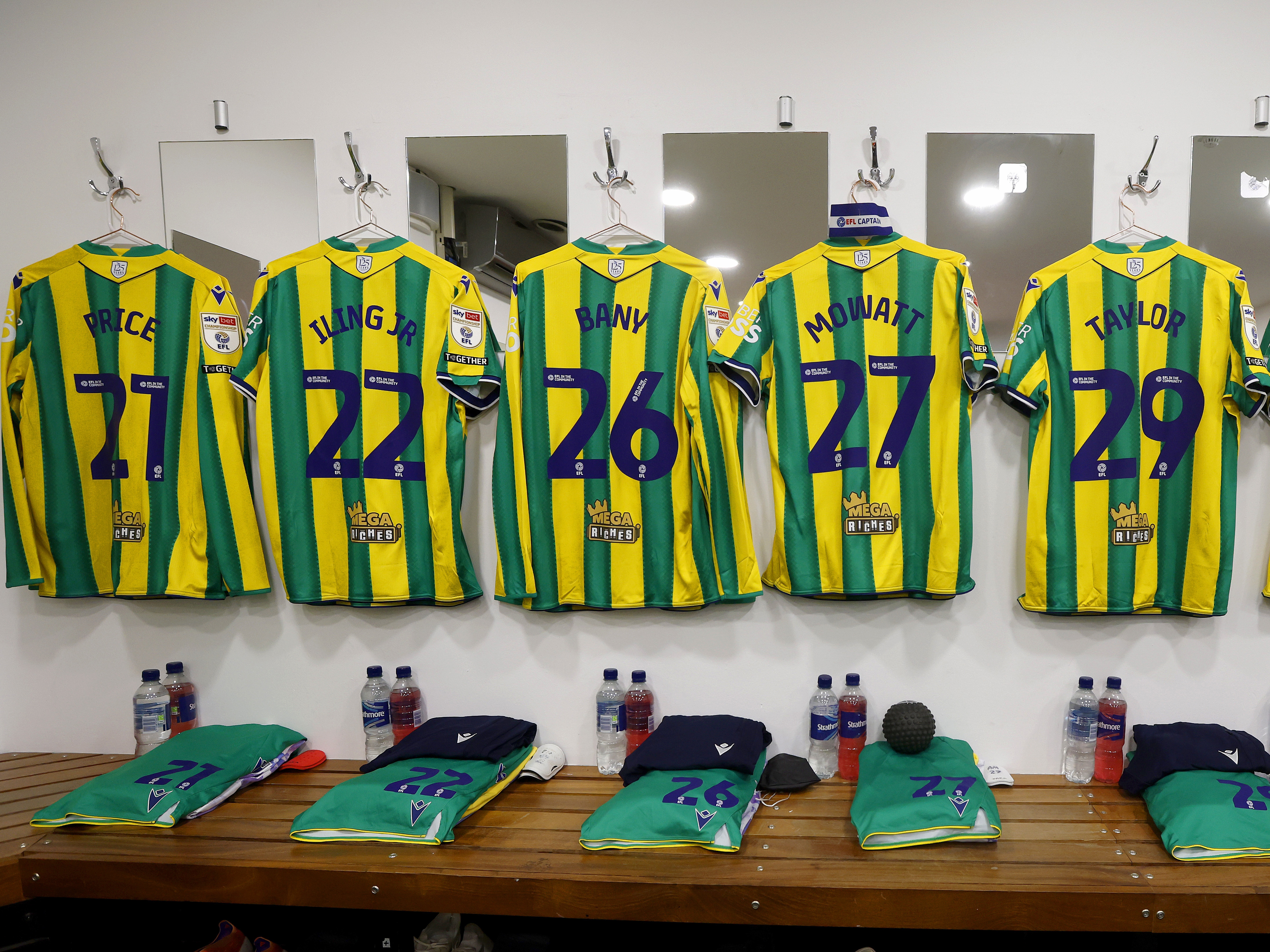 Green and yellow shirts hanging up in a dressing room with names and numbers on show