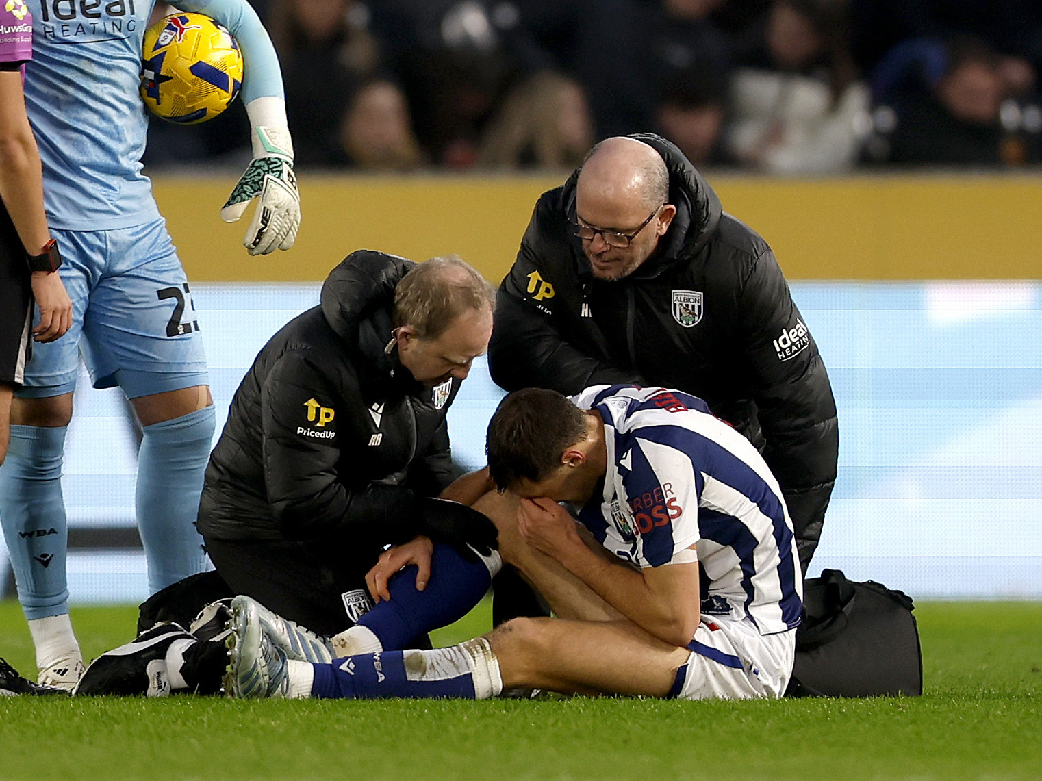 Krystian Bielik is assessed by medical staff on the pitch after picking up an injury 