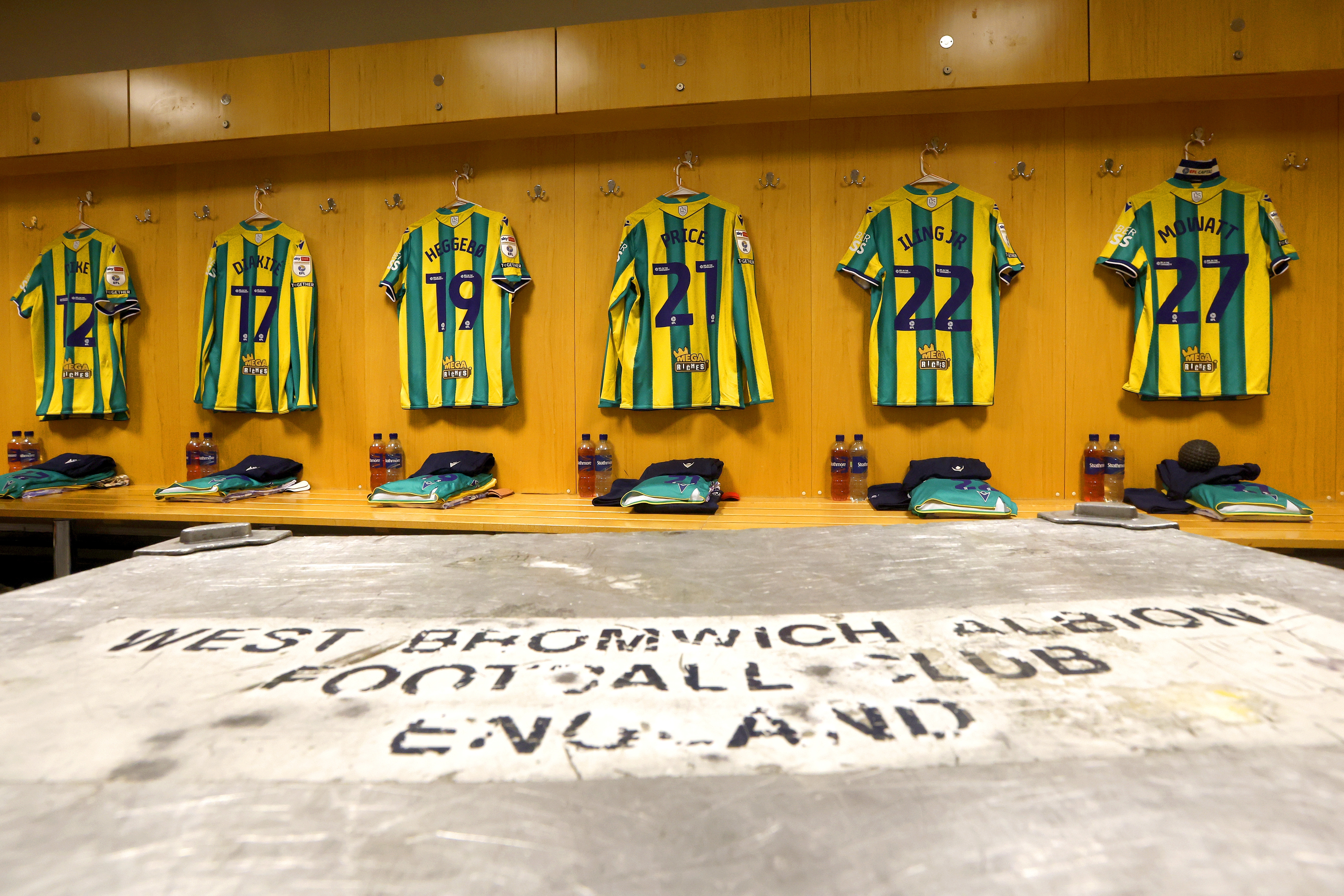 Green and yellow shirts hanging up in a dressing room with names and numbers on display