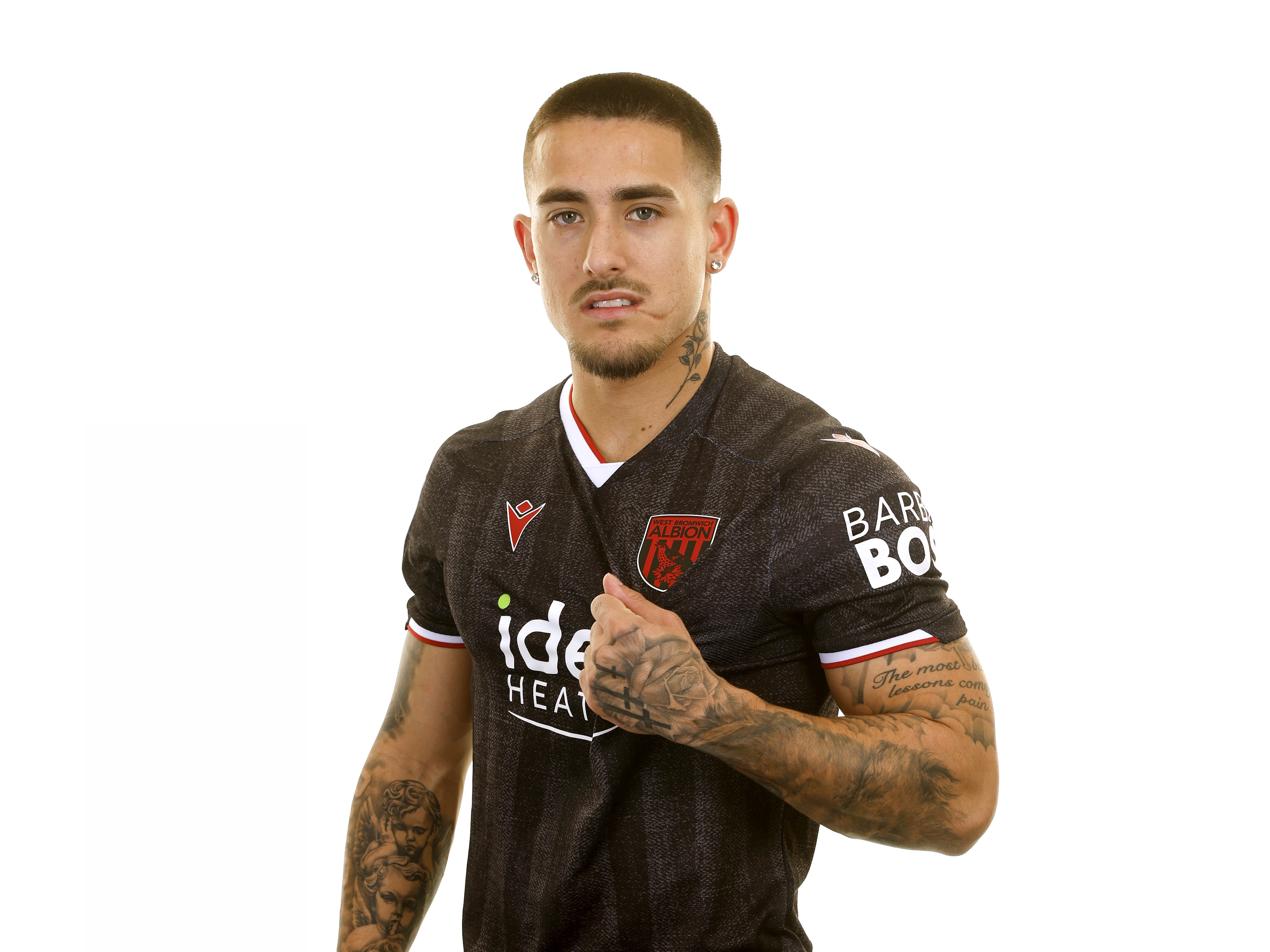 Danny Imray looking at the camera and pulling the black away shirt while stood in front of a white background 
