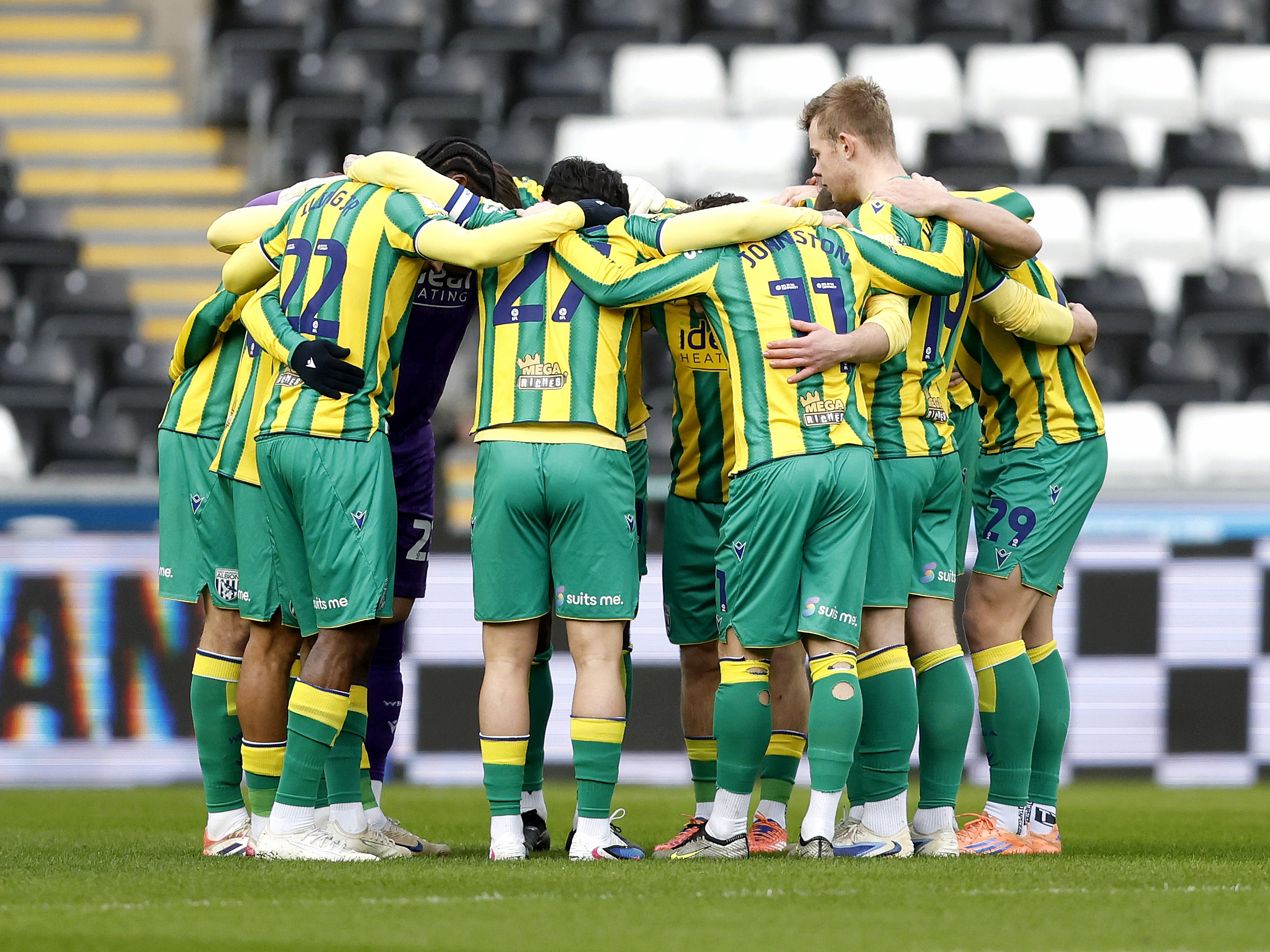 Albion in a pre-match huddle in the green and yellow away kit 
