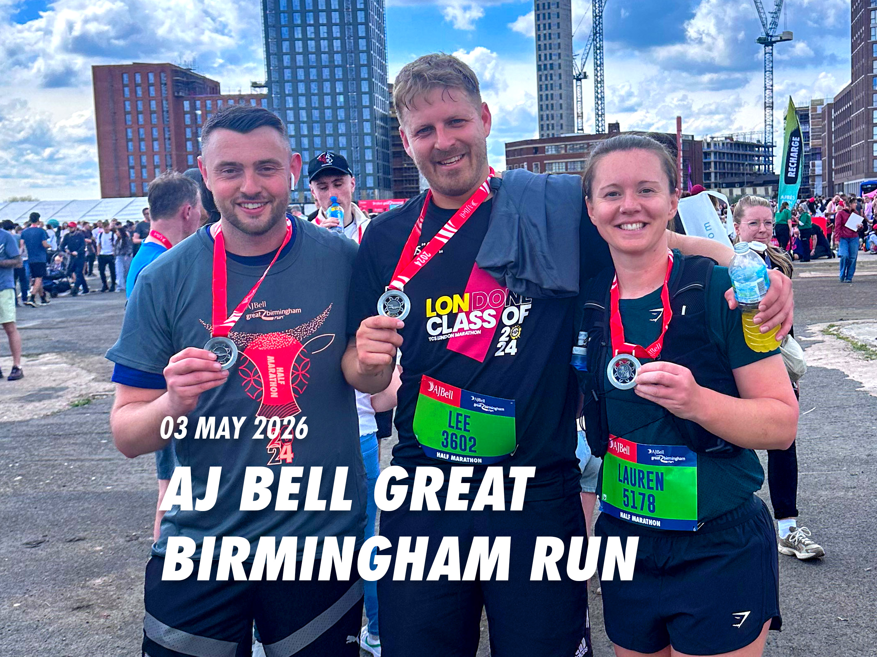 Three people are posing for a photo after completing a race. They are wearing medals and holding water bottles.