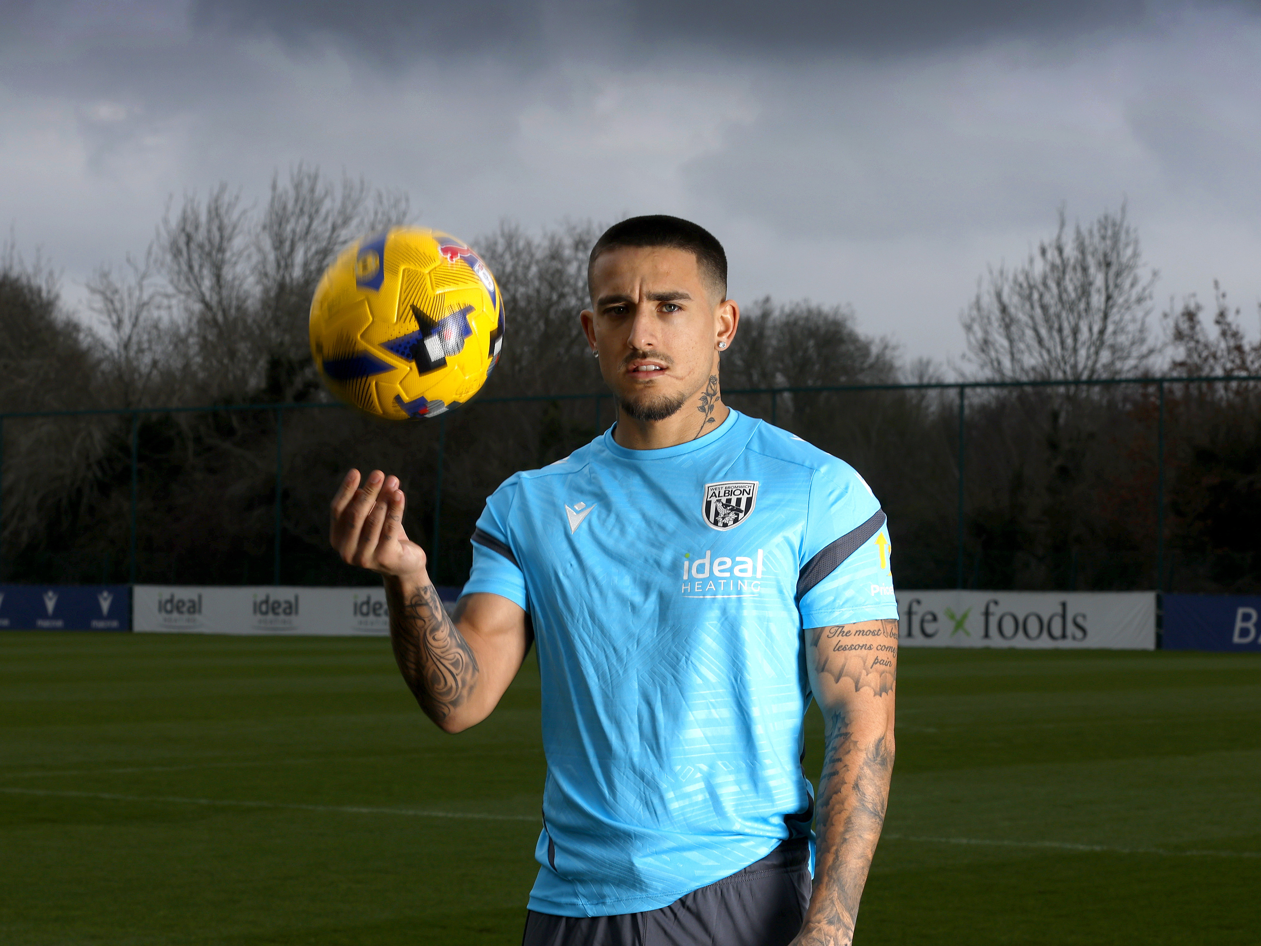 Danny Imray smiling at the camera while holding a ball out on a training pitch