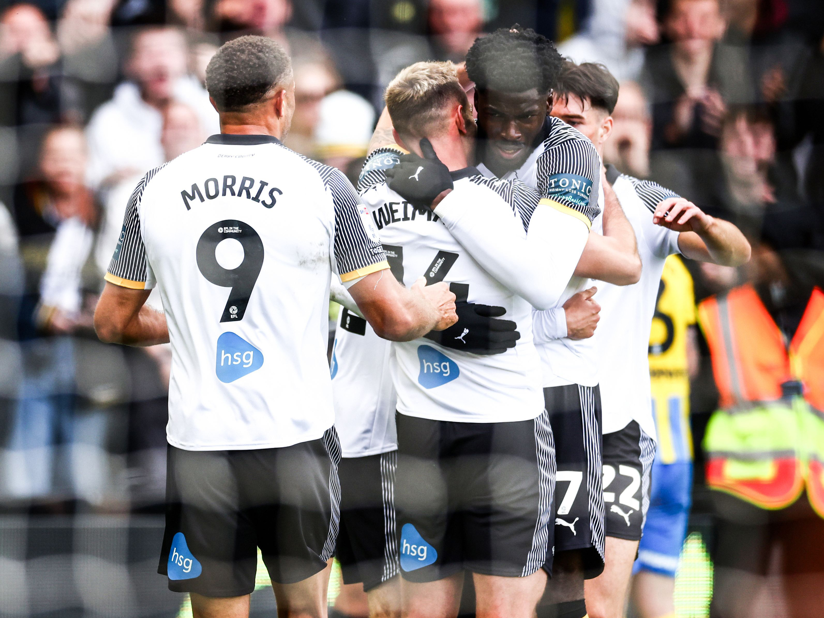 Three Derby players celebrating a goal scored in their home shirt 