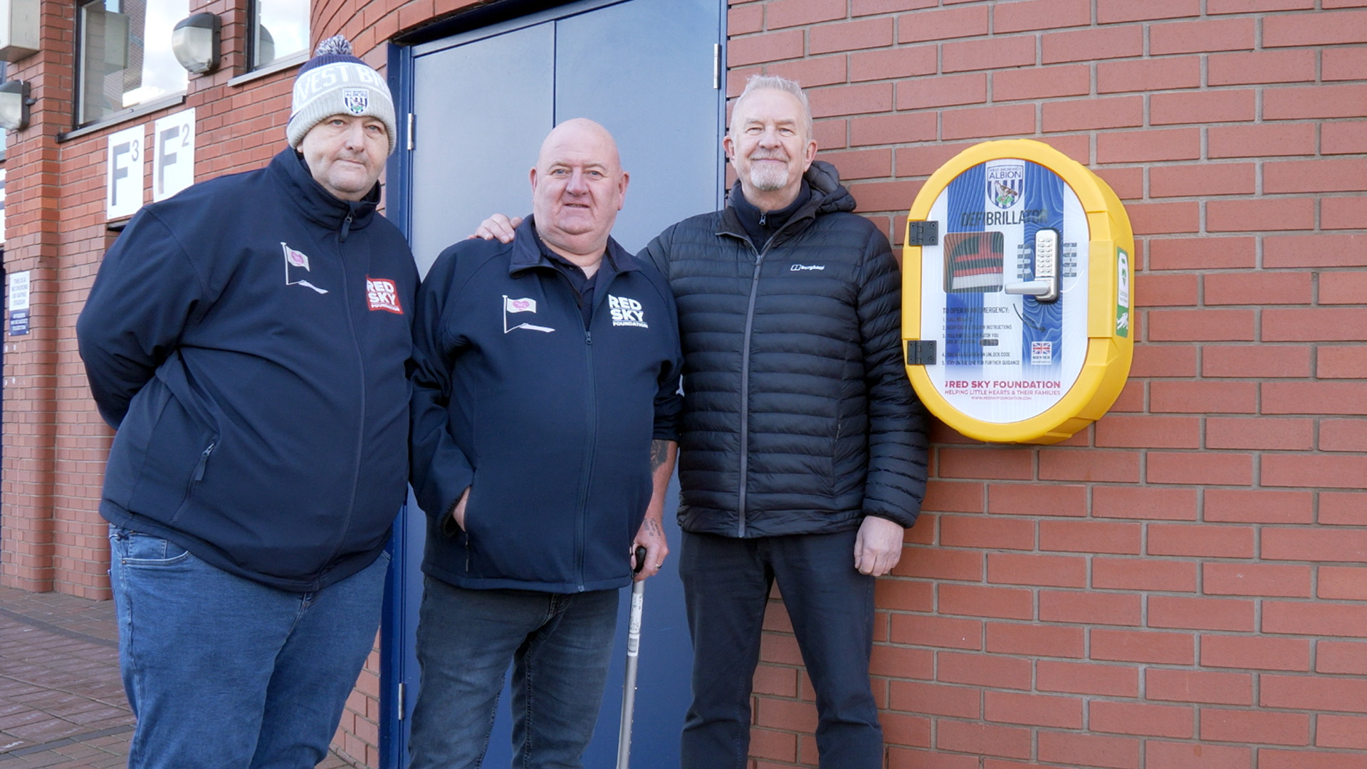 Richard Sant, Paul Gregory and Chris Harris pose next to a defibrillator