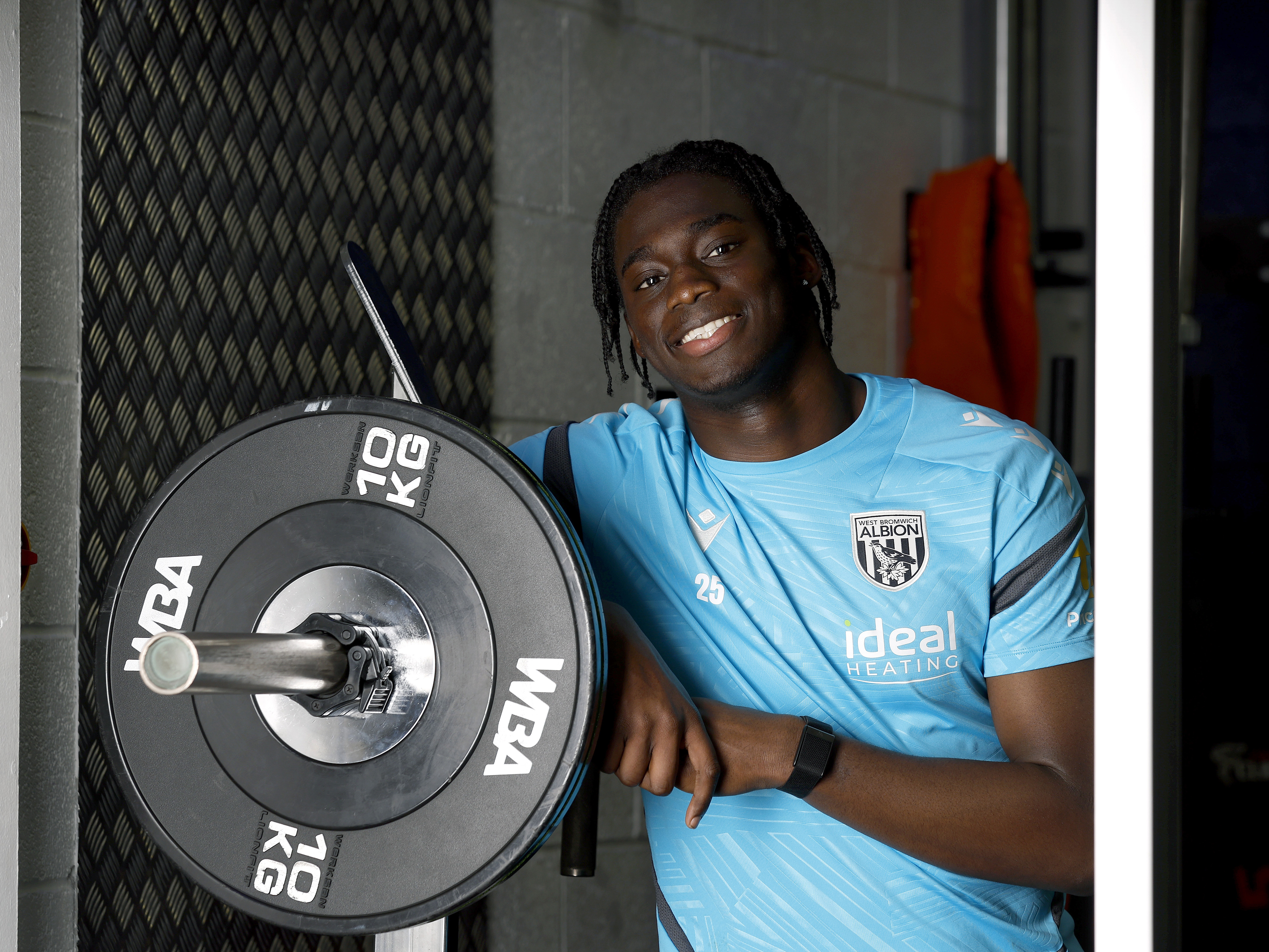 Hindolo Mustapha smiling at the camera while leaning in the gym