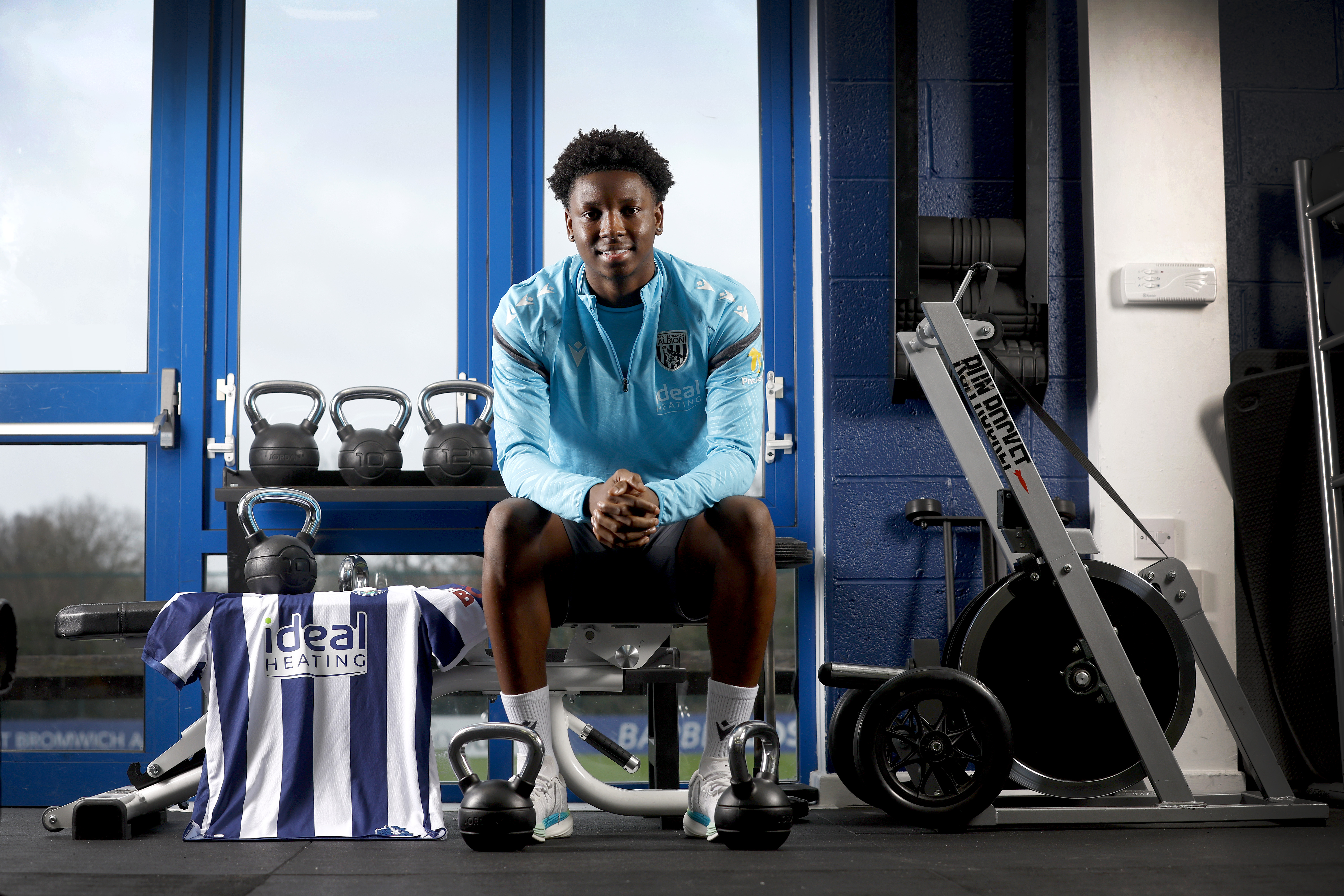 Jamal Jimoh-Aloba sat in the gym smiling at the camera with a home WBA shirt next to him