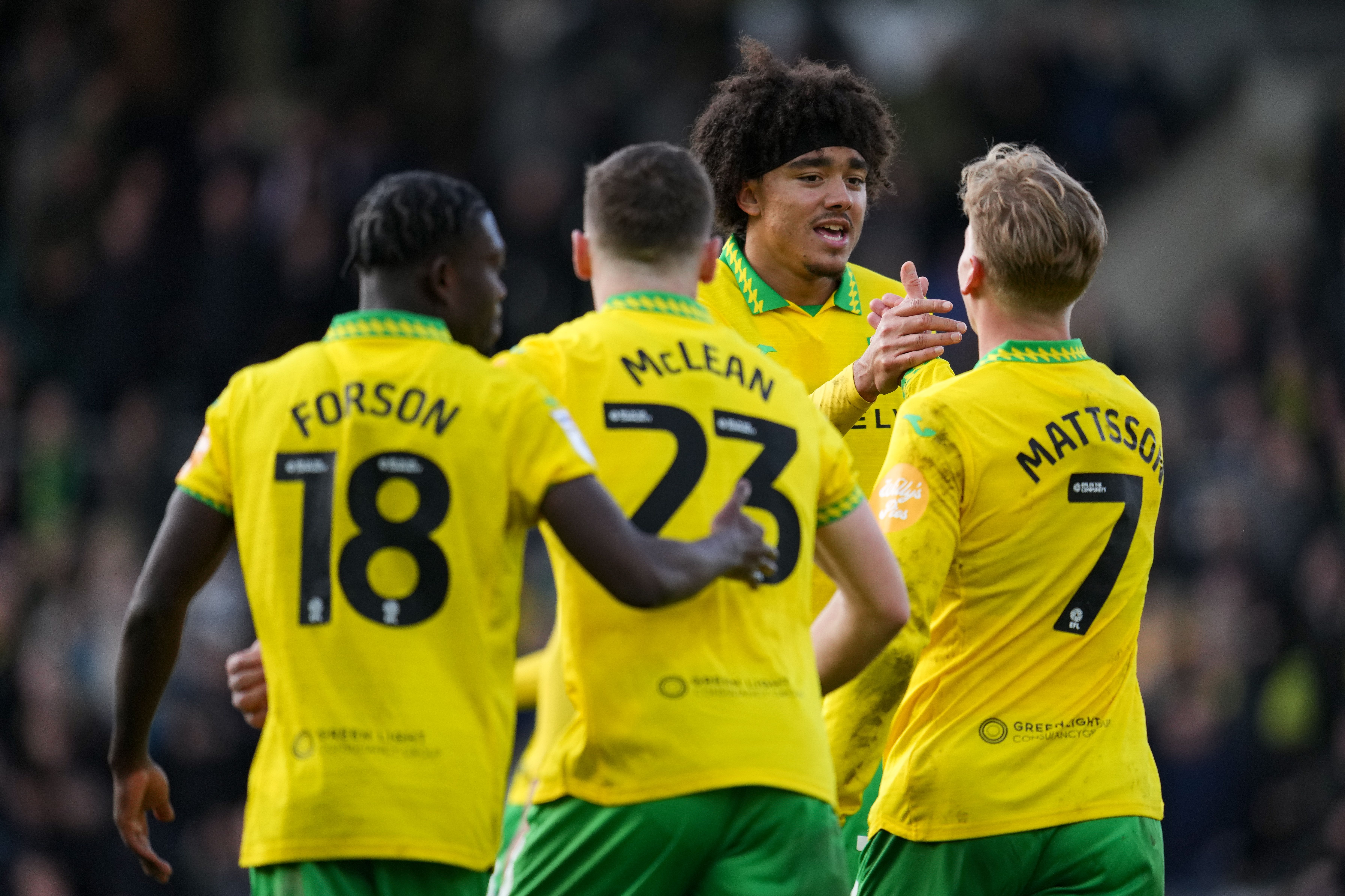 Four Norwich players in their home kit celebrate a goal