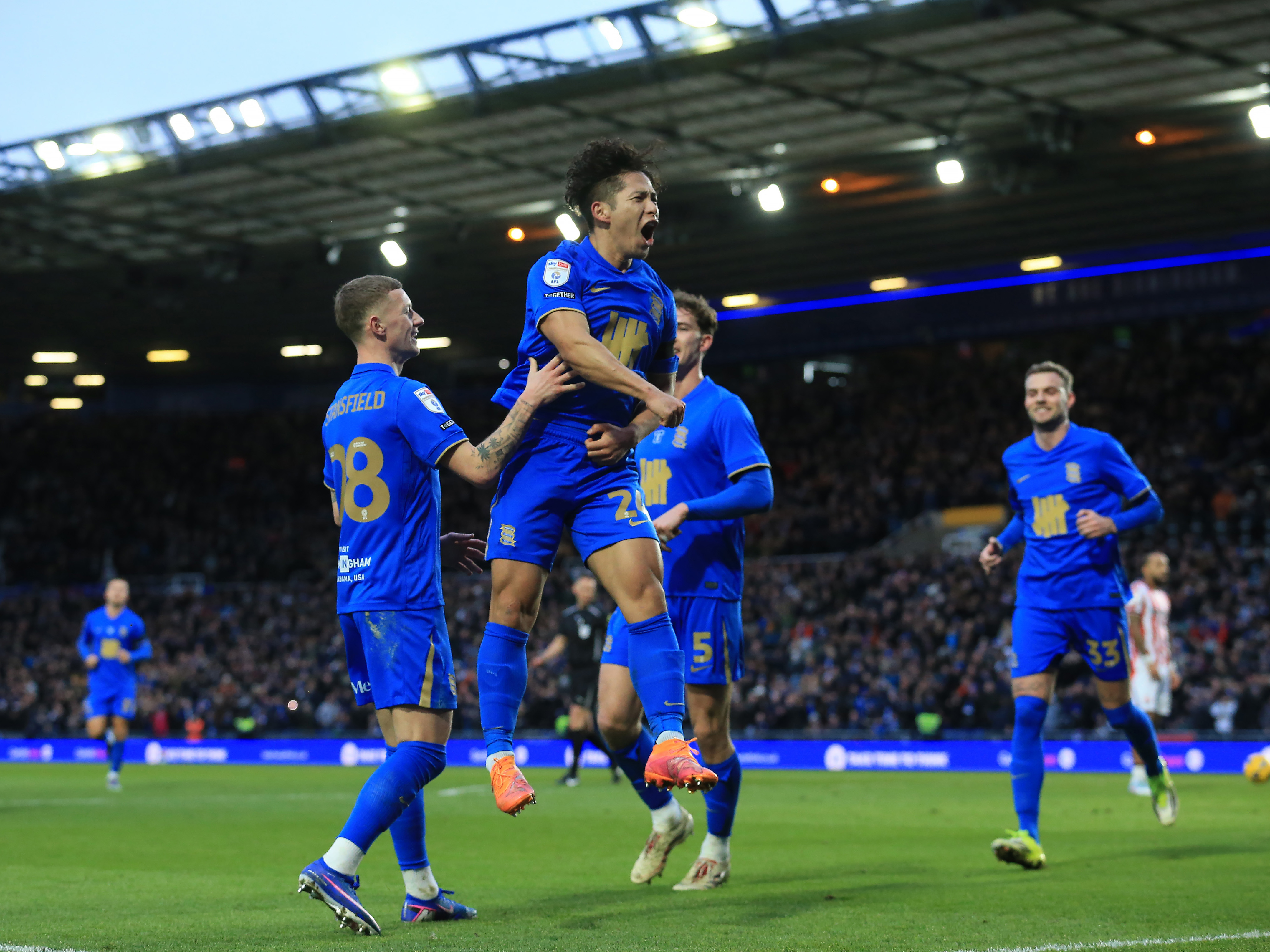 Four Blues players celebrating a goal scored in their home kit at their home stadium