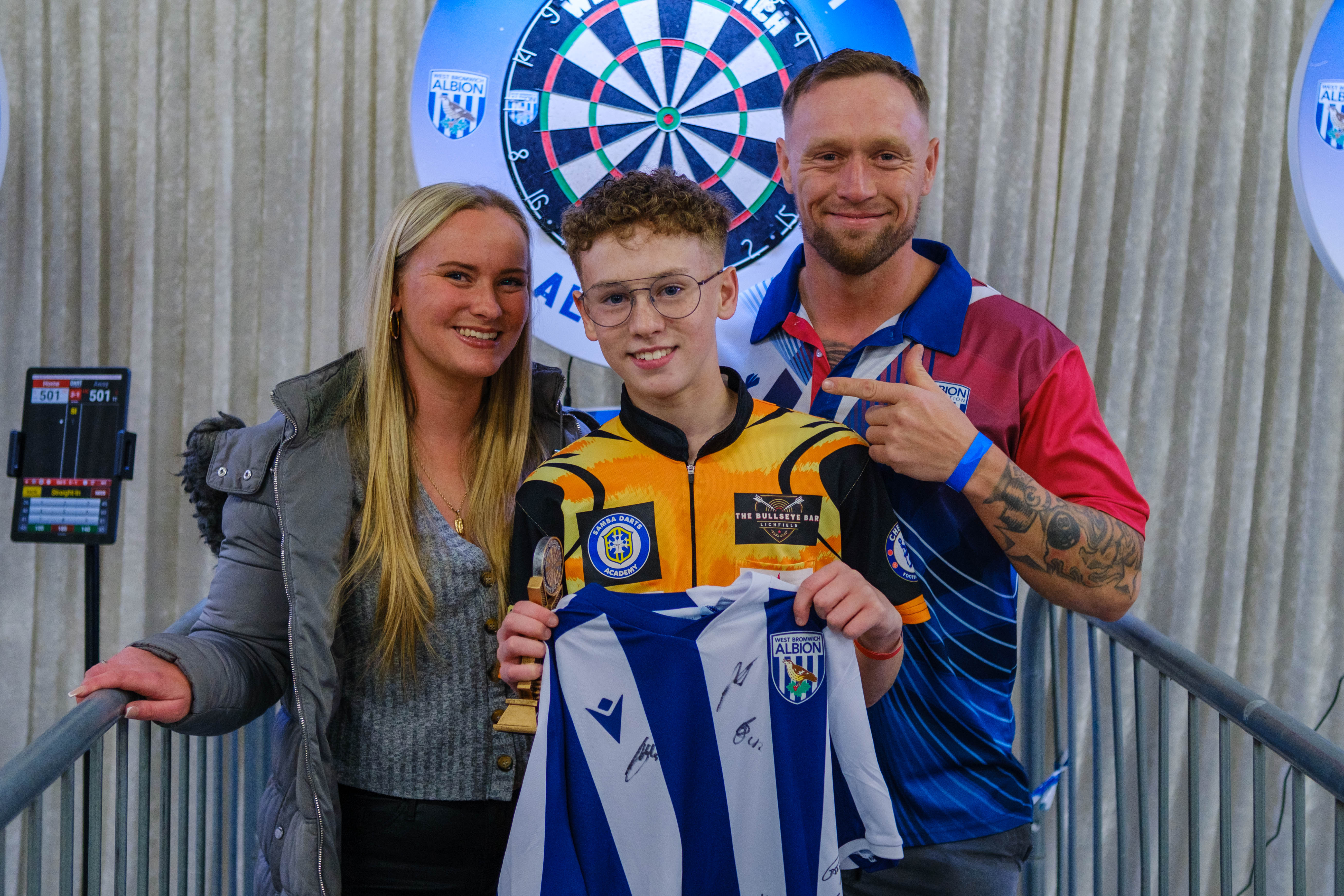 Junior champion Codey with his parents holding a signed shirt and winners trophy.