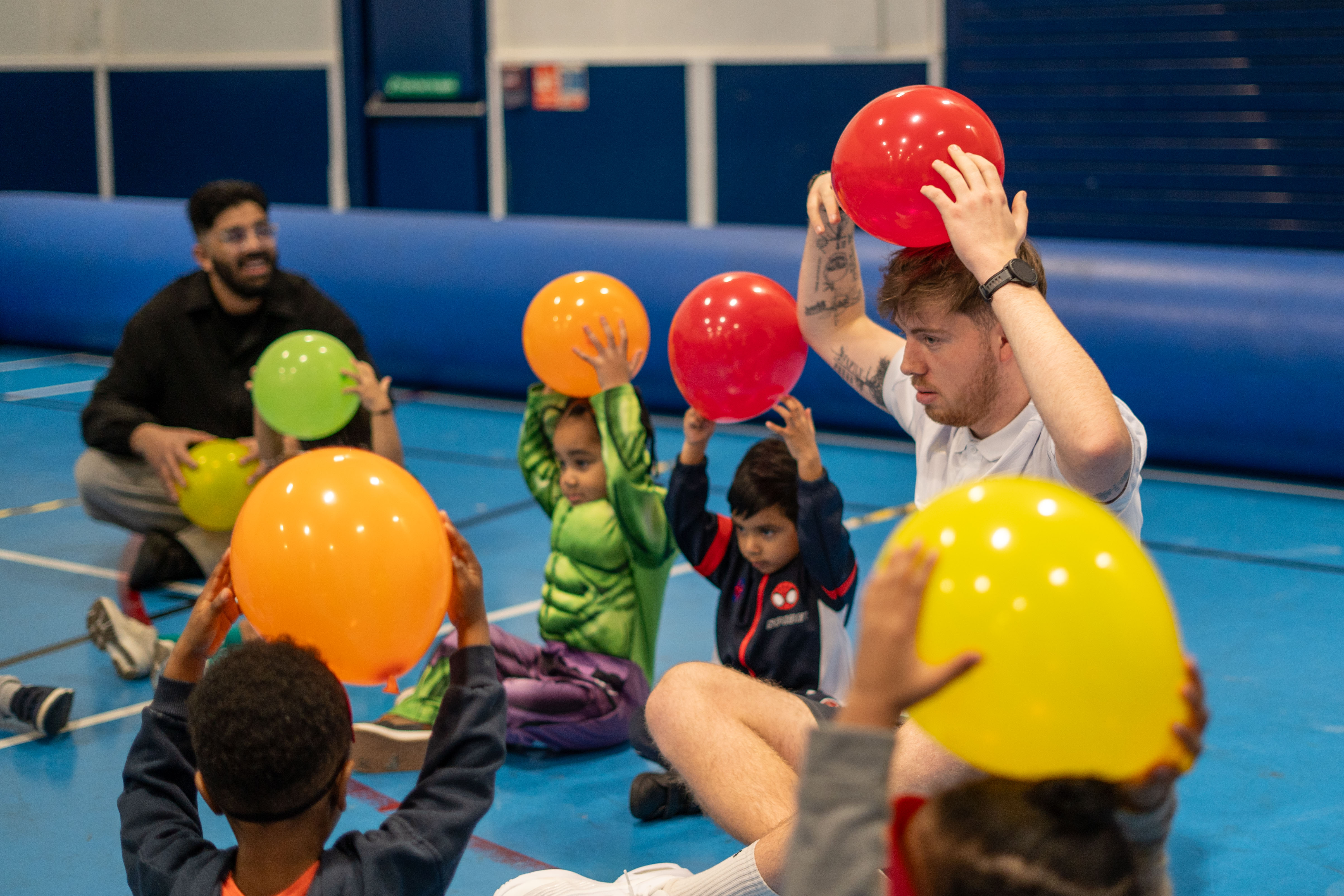 Coach and participants holding balloons on their heads.