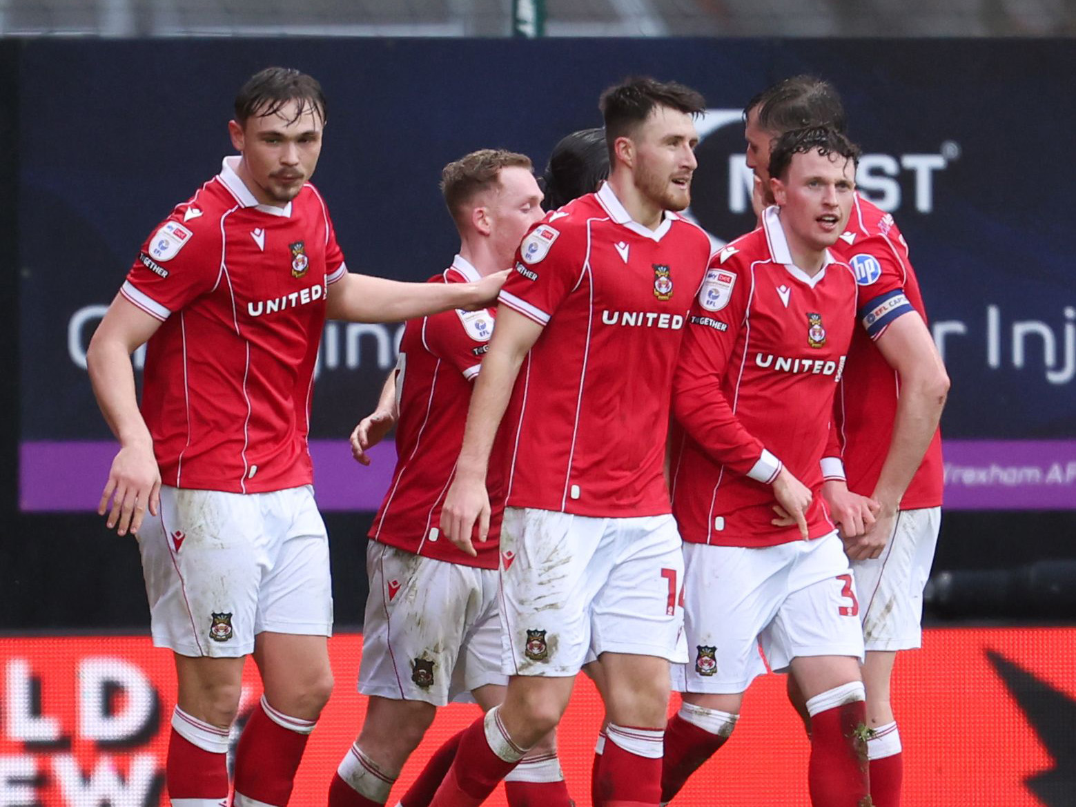 Several Wrexham players celebrate a goal in their home kit 