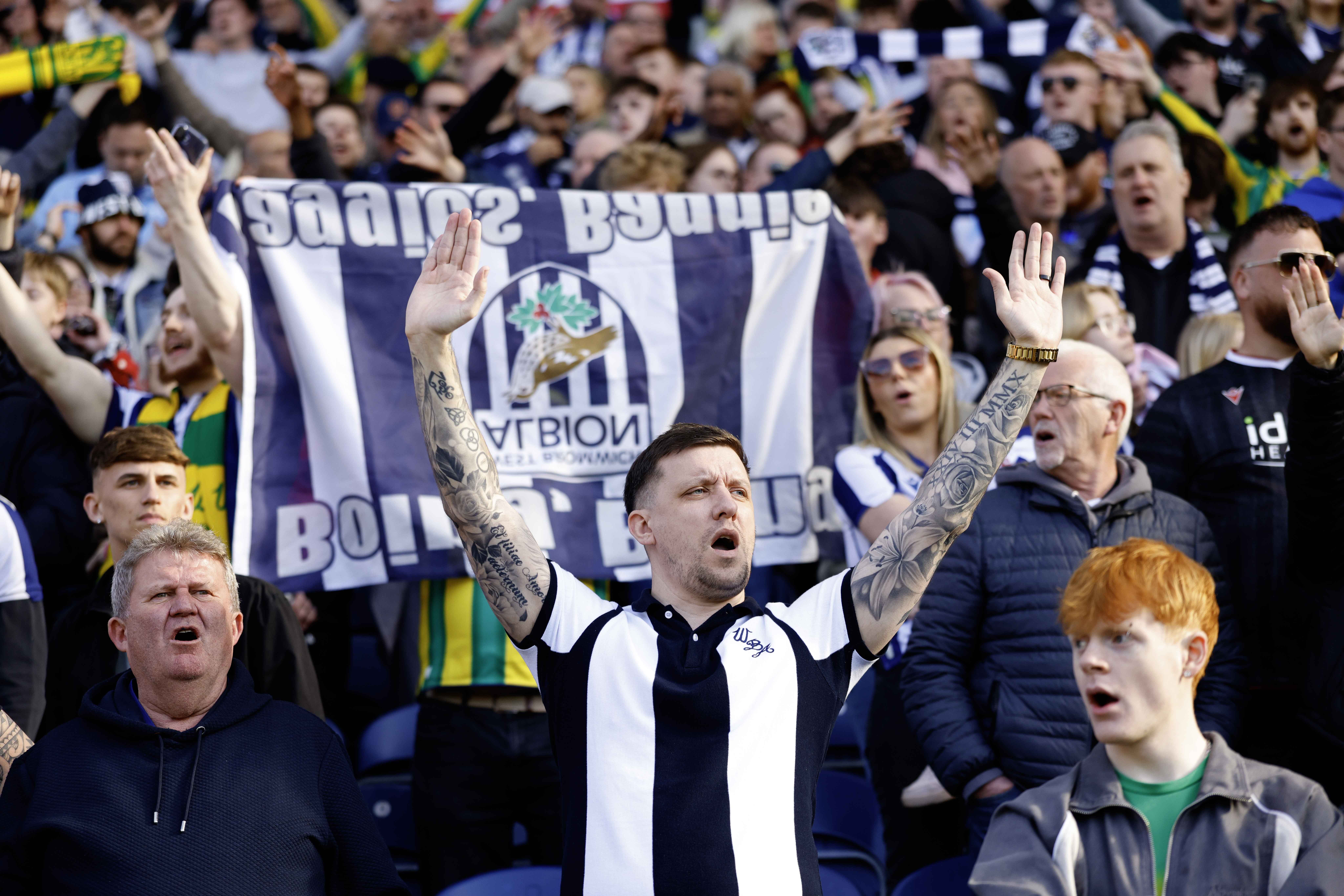 A general view of WBA fans cheering at a game with a flag in the background