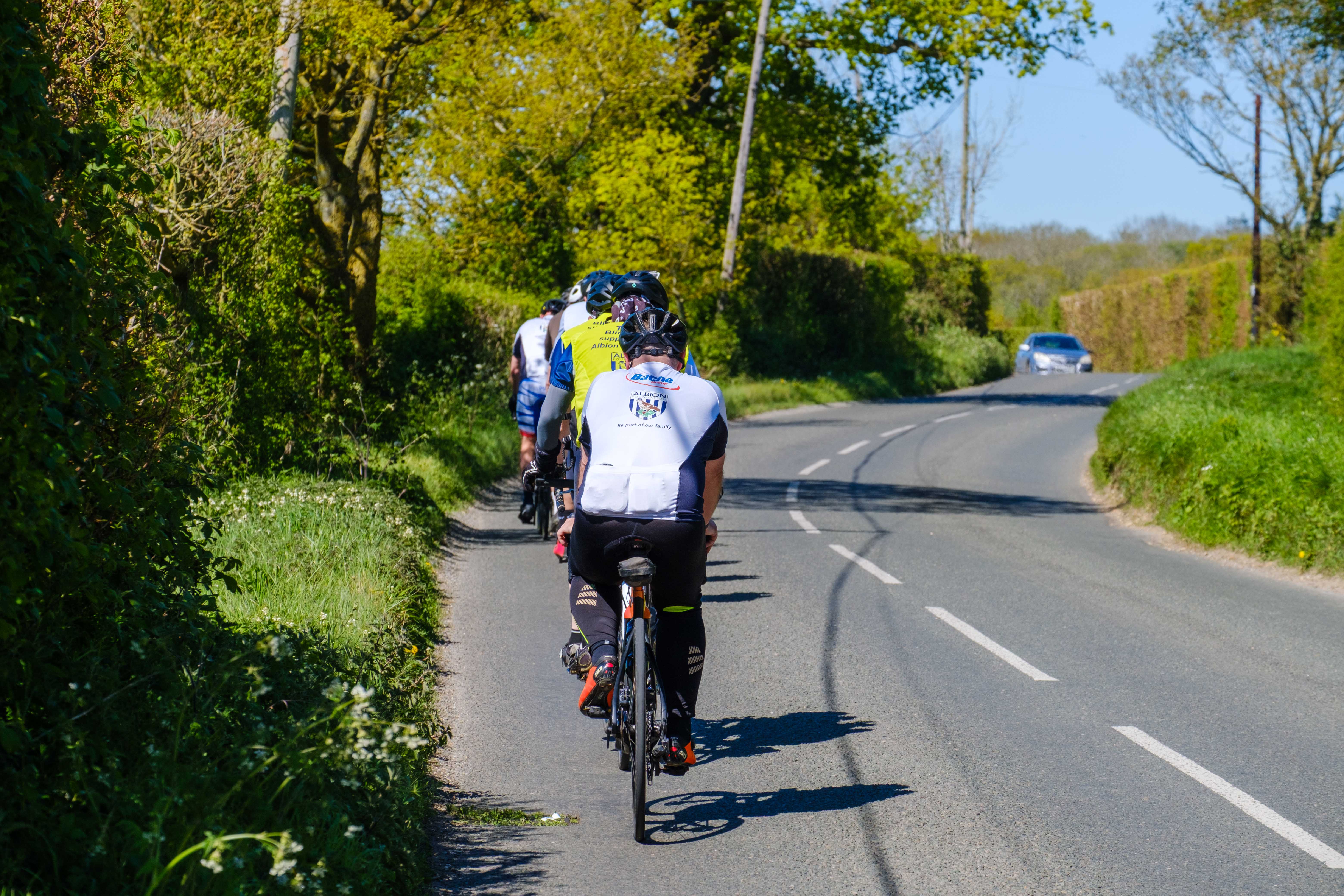 Backs of cyclists riding down a country road.