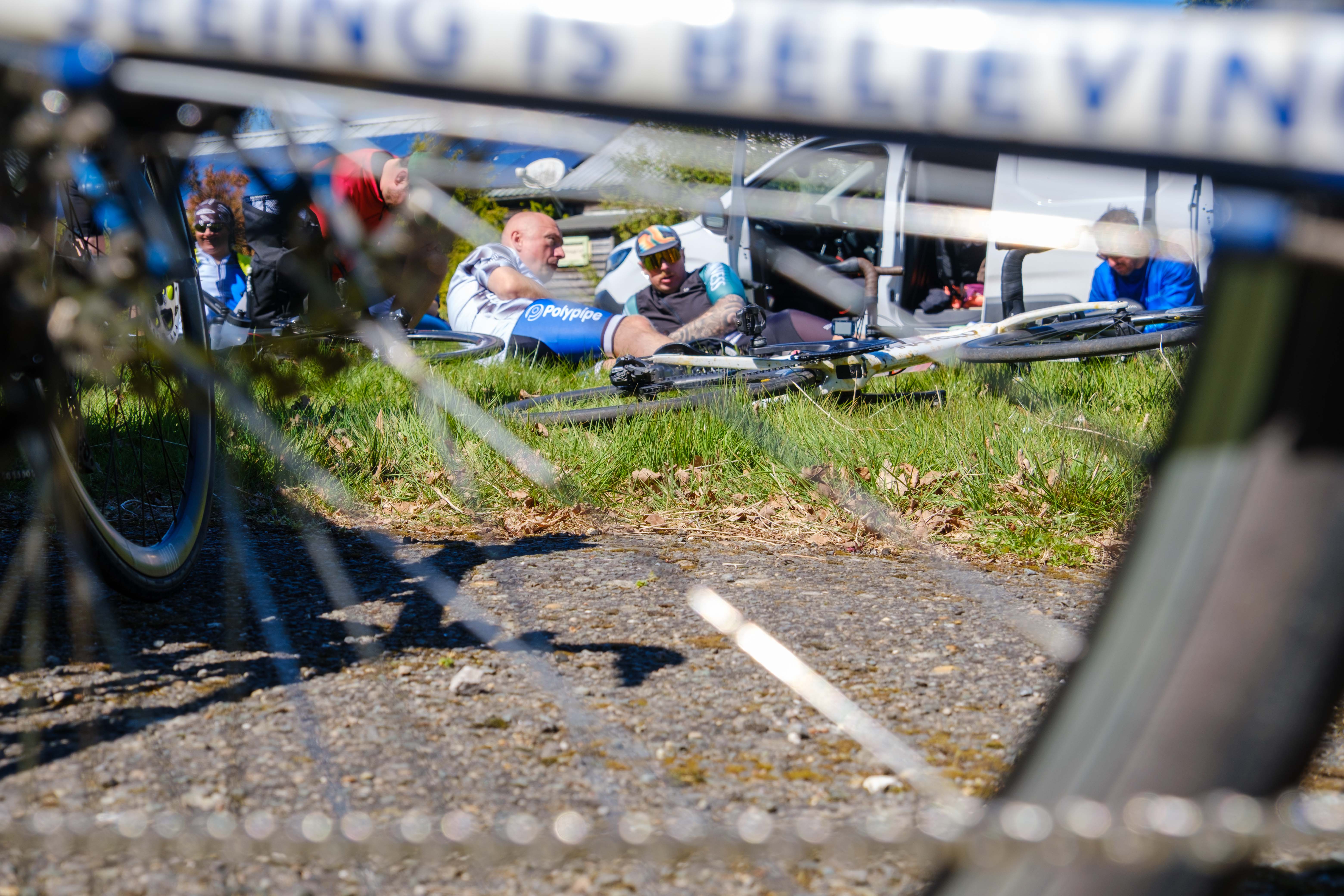 Cyclists laying on grass, shoot through wheel spokes.