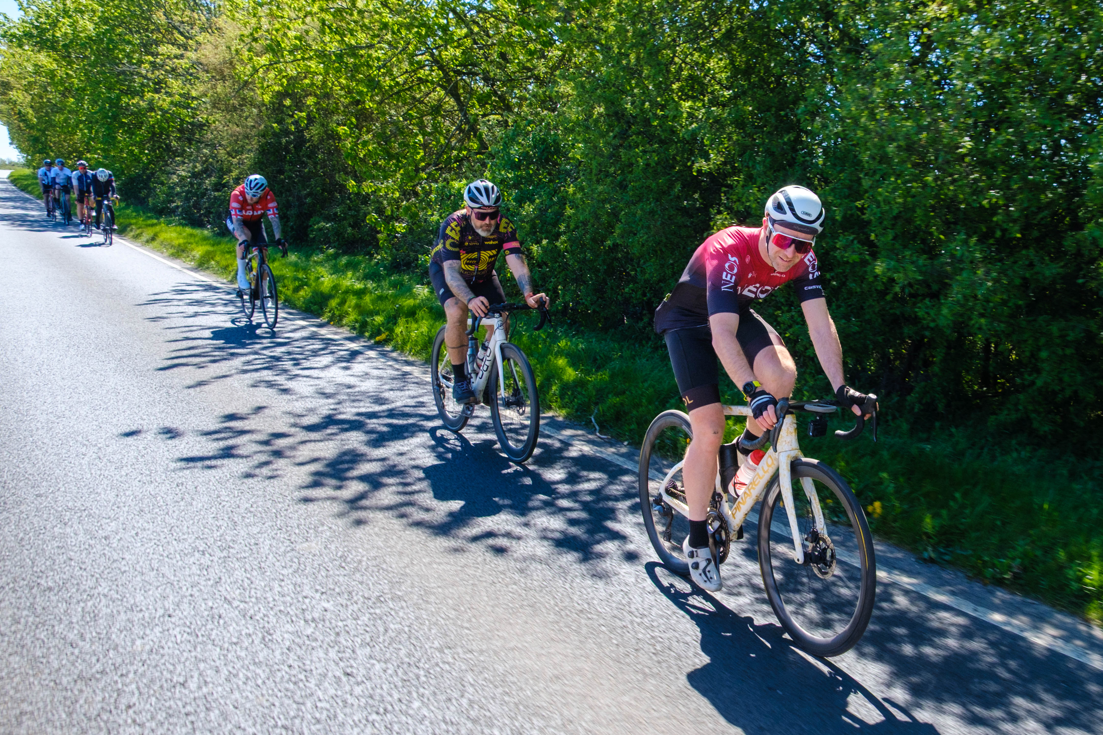 Three cyclist riding down a country road.