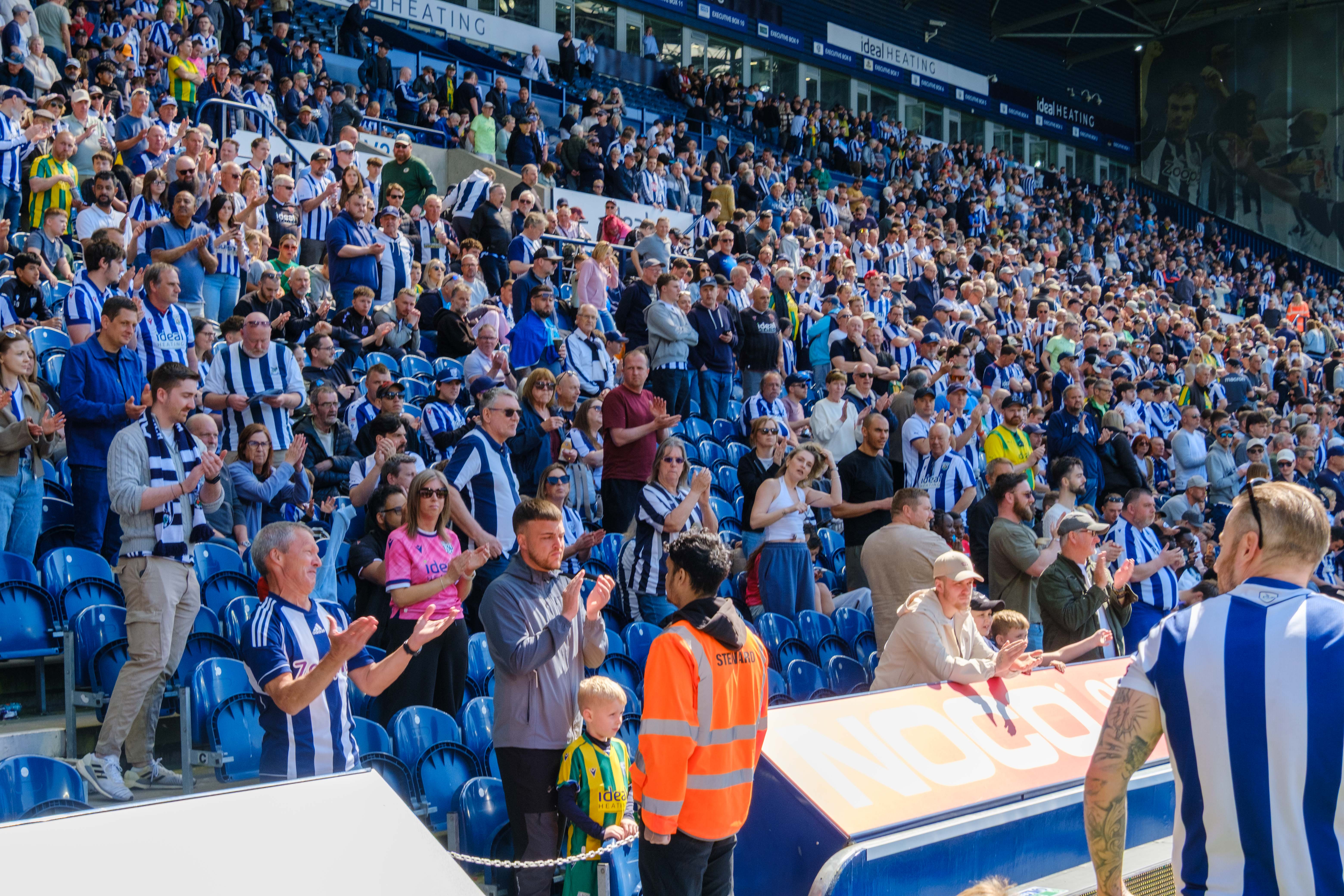 Fans applauding cyclists during lap of honour.