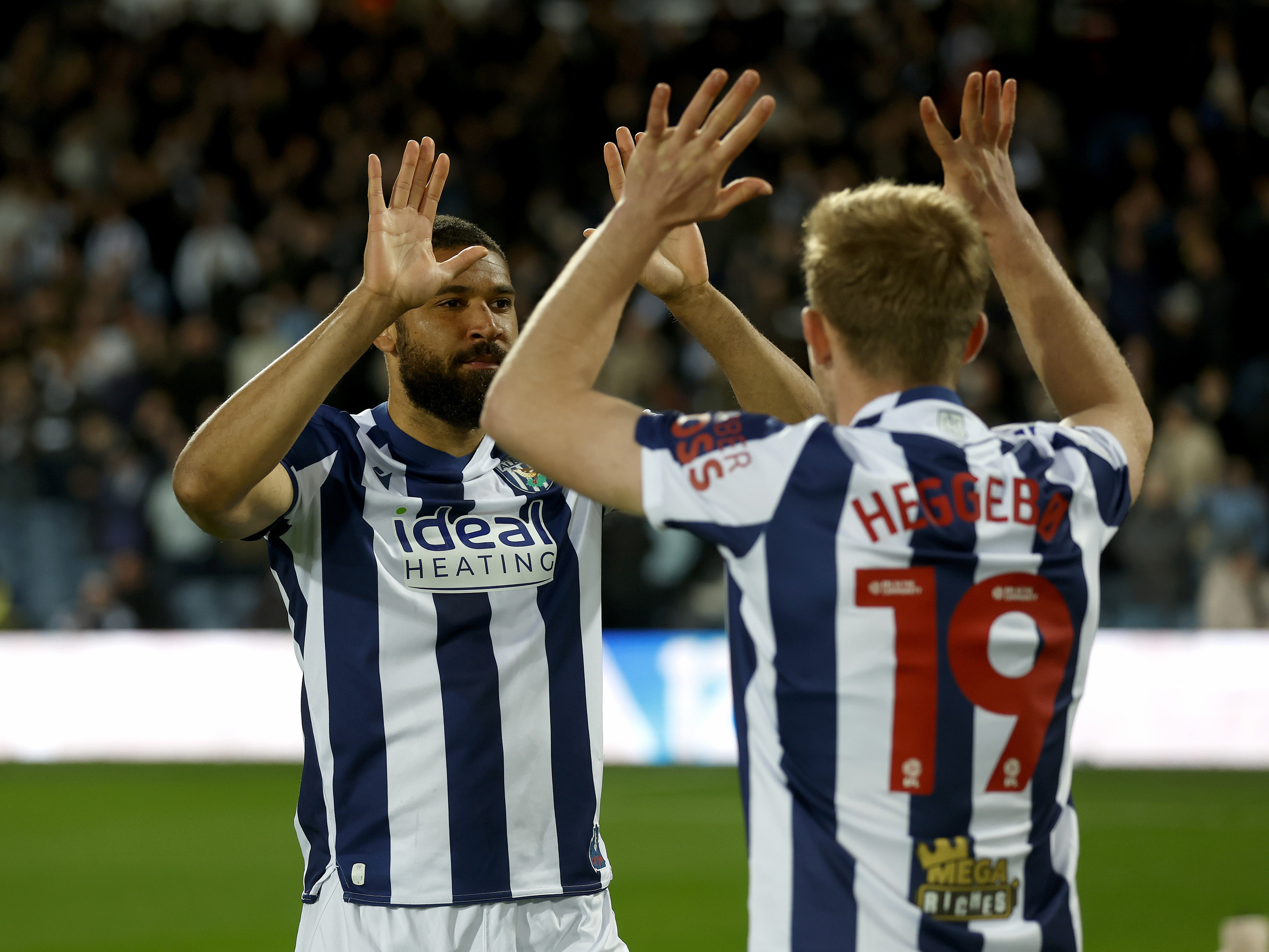 George Campbell and Aune Heggebø high five on the pitch before a game in the home kit 