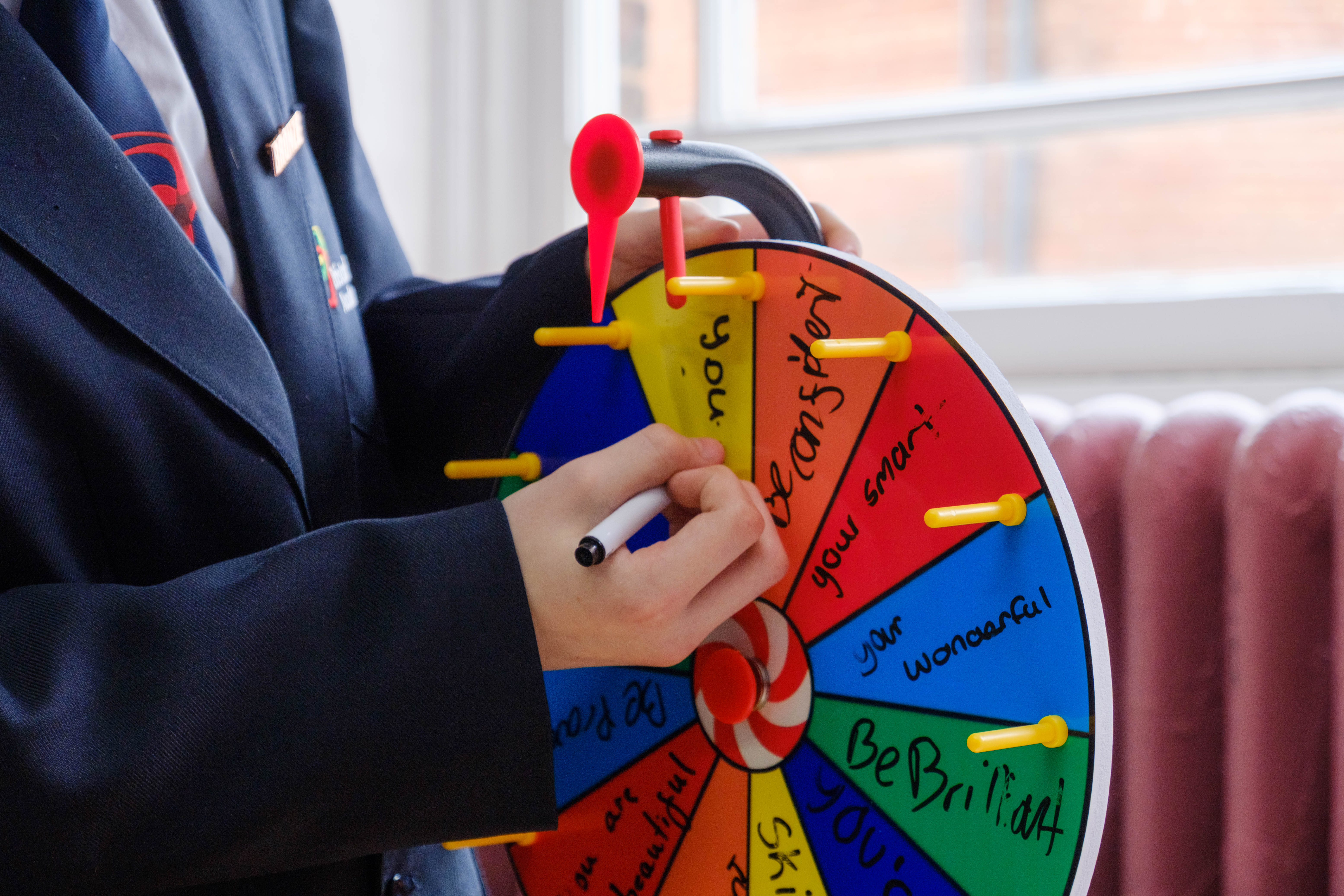 Close-up of student writing positive comments on the spinning wheel.