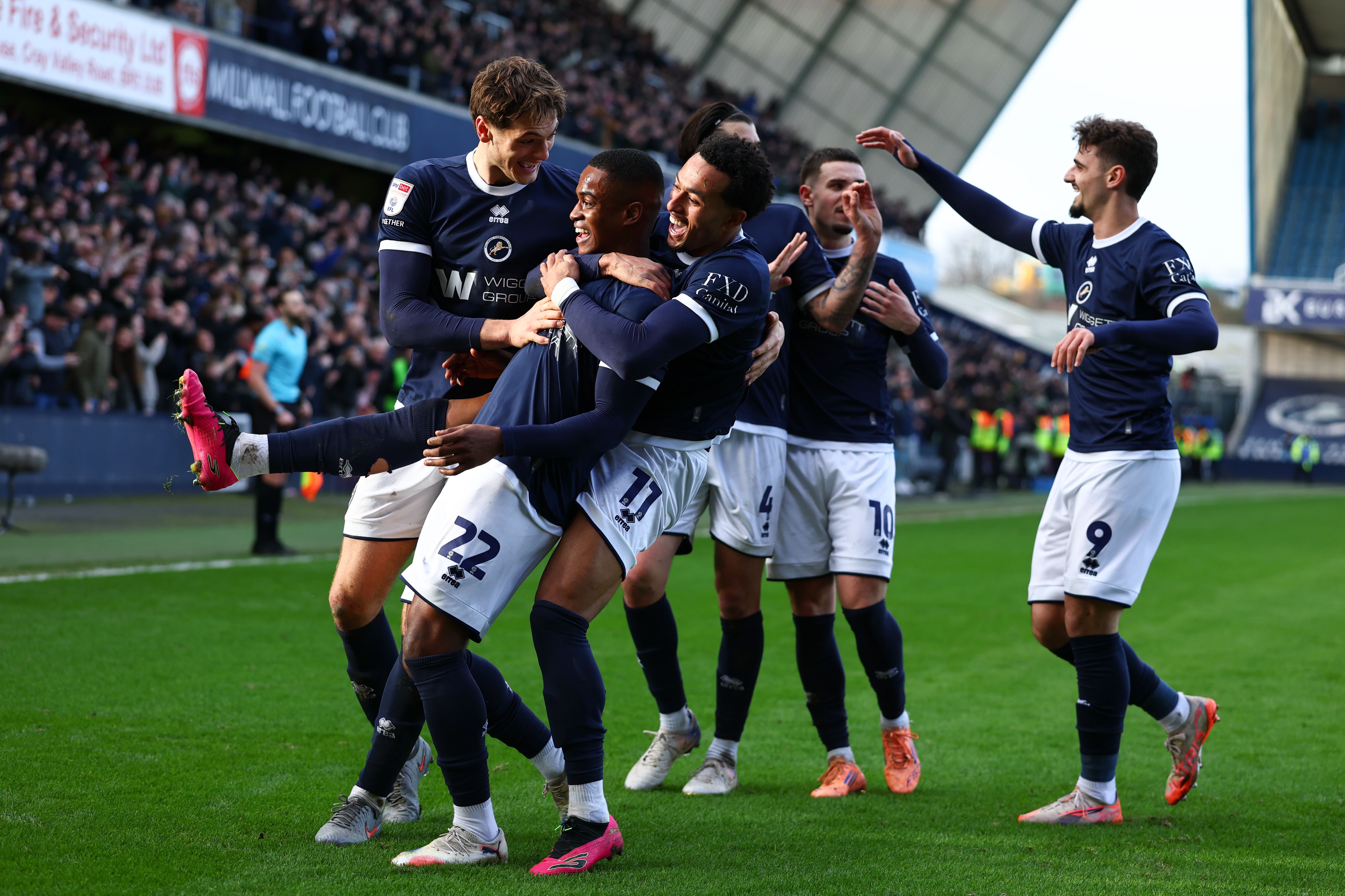 Several Millwall players celebrating a goal in their home kit at The Den