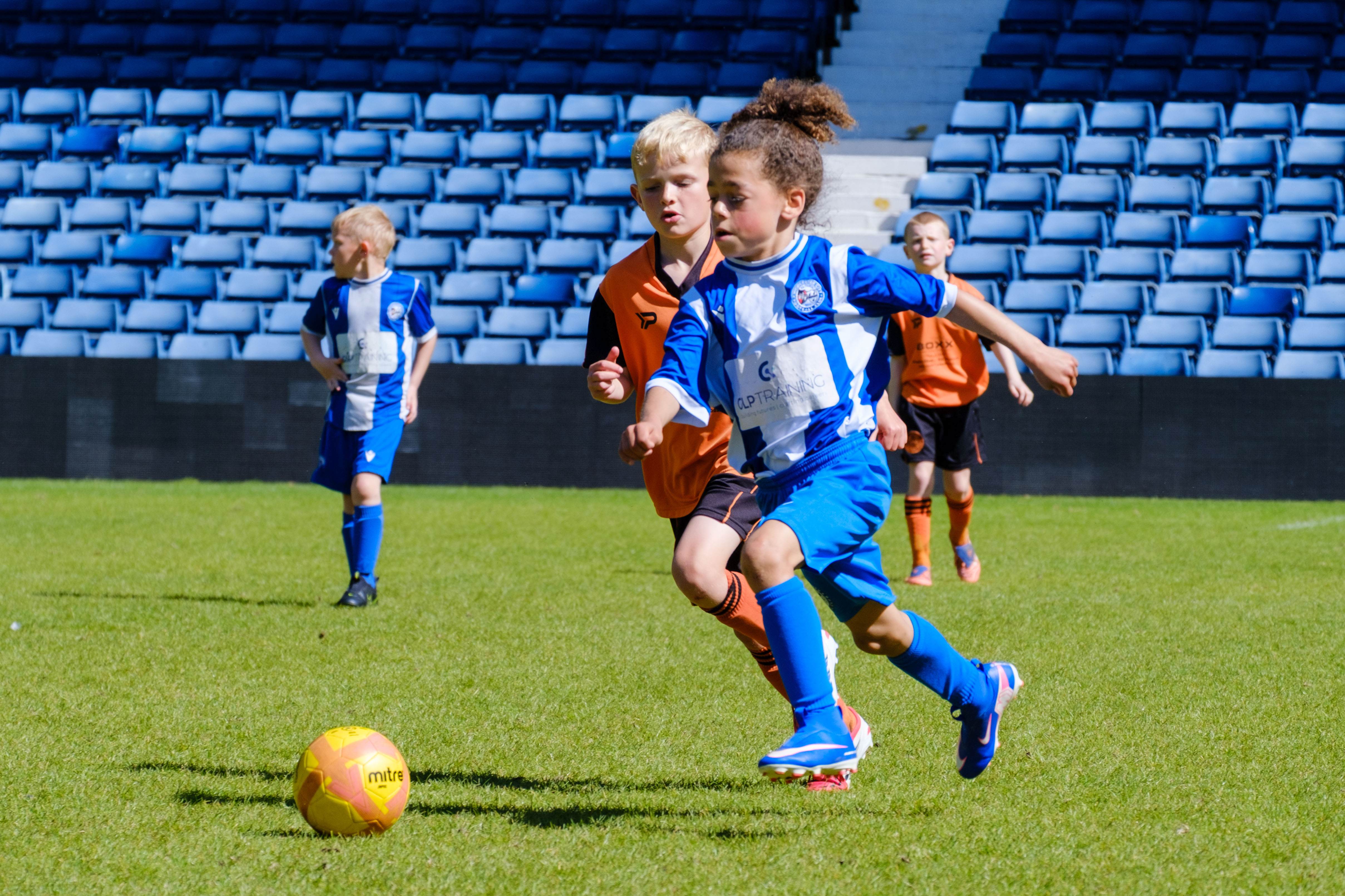 Players running onto the ball, shielding off defender.